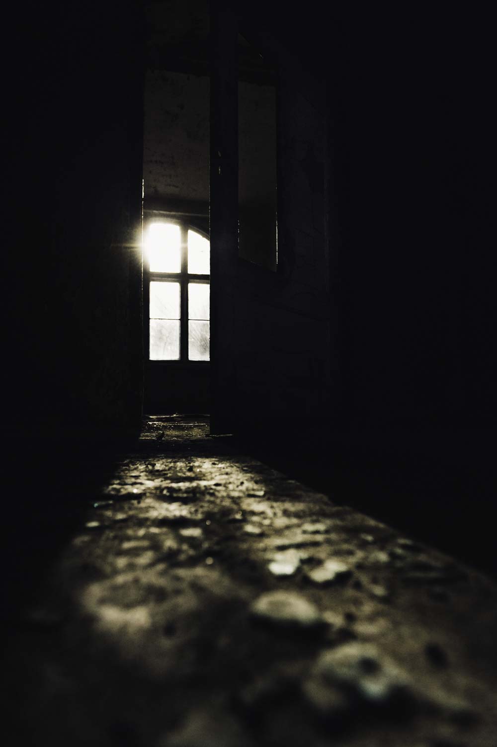 Glassplitter liegen auf dem Boden. Die Sonne scheint durch eine offen stehende Tür in den Hauptgang.