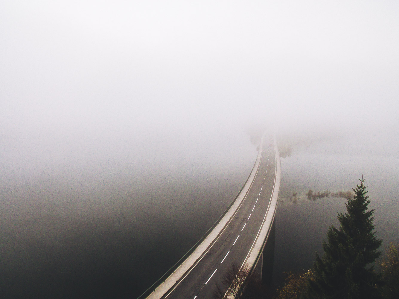 Die Straße verschwindet in den tiefhängenden Wolken. Das andere Ufer des Sylvensteinsees ist kaum zu erkennen.