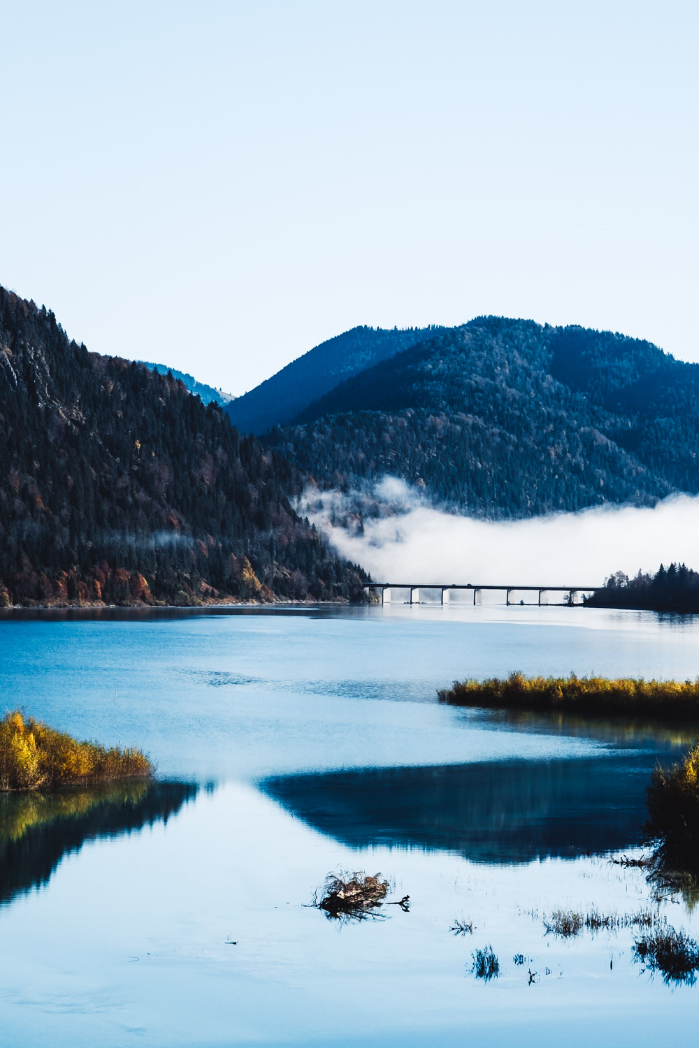 Blick mit der Drohne über die in Sylvensteinsee mündende Isar. Der See ist immer noch von einer dicken Wolkendecke bedeckt.