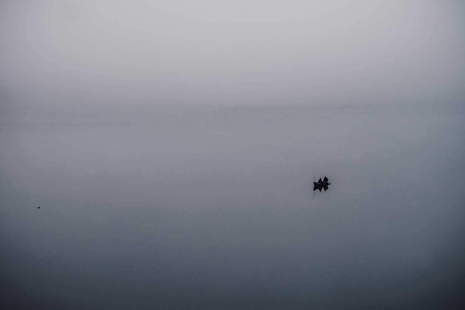 Angler nutzen die morgendliche Ruhe. Sie umhüllt vom Nebel der Wolken.