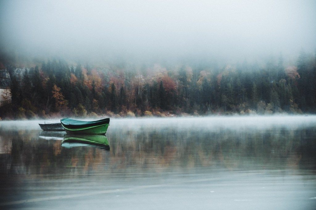 Einige Boote lagen ruhig und festgemacht am Ufer des Sees. Sie spiegelten sich perfekt im glatten Wasser.
