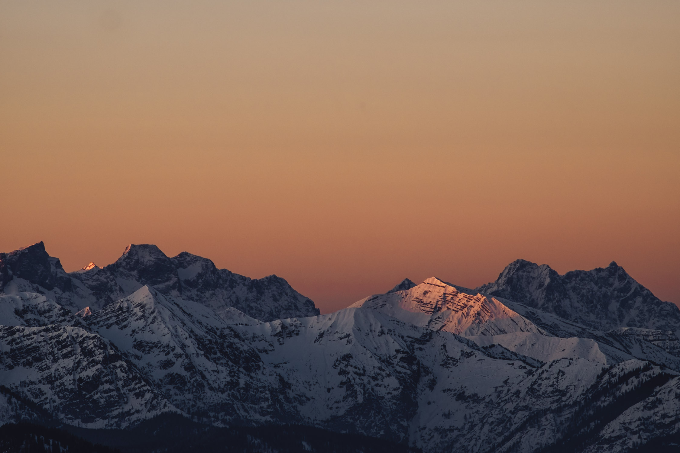 Das erste Sonnenlicht erhellt die umliegenden Gipfel.