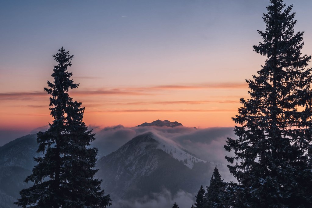 Die Wolken lösten sich langsam im Licht der aufgehenden Sonne auf und krochen über den Gipfel des Jochbergs.