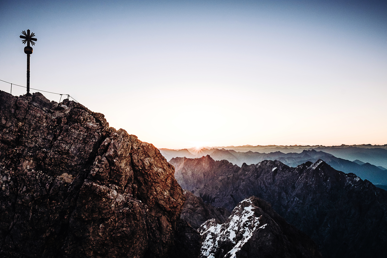 Im Juni geht es hoch hinaus. Das Motiv zeigt den Sonnenaufgang auf der Zugspitze und die Sonne wie gerade über die Gipfel der Alpen steigt.