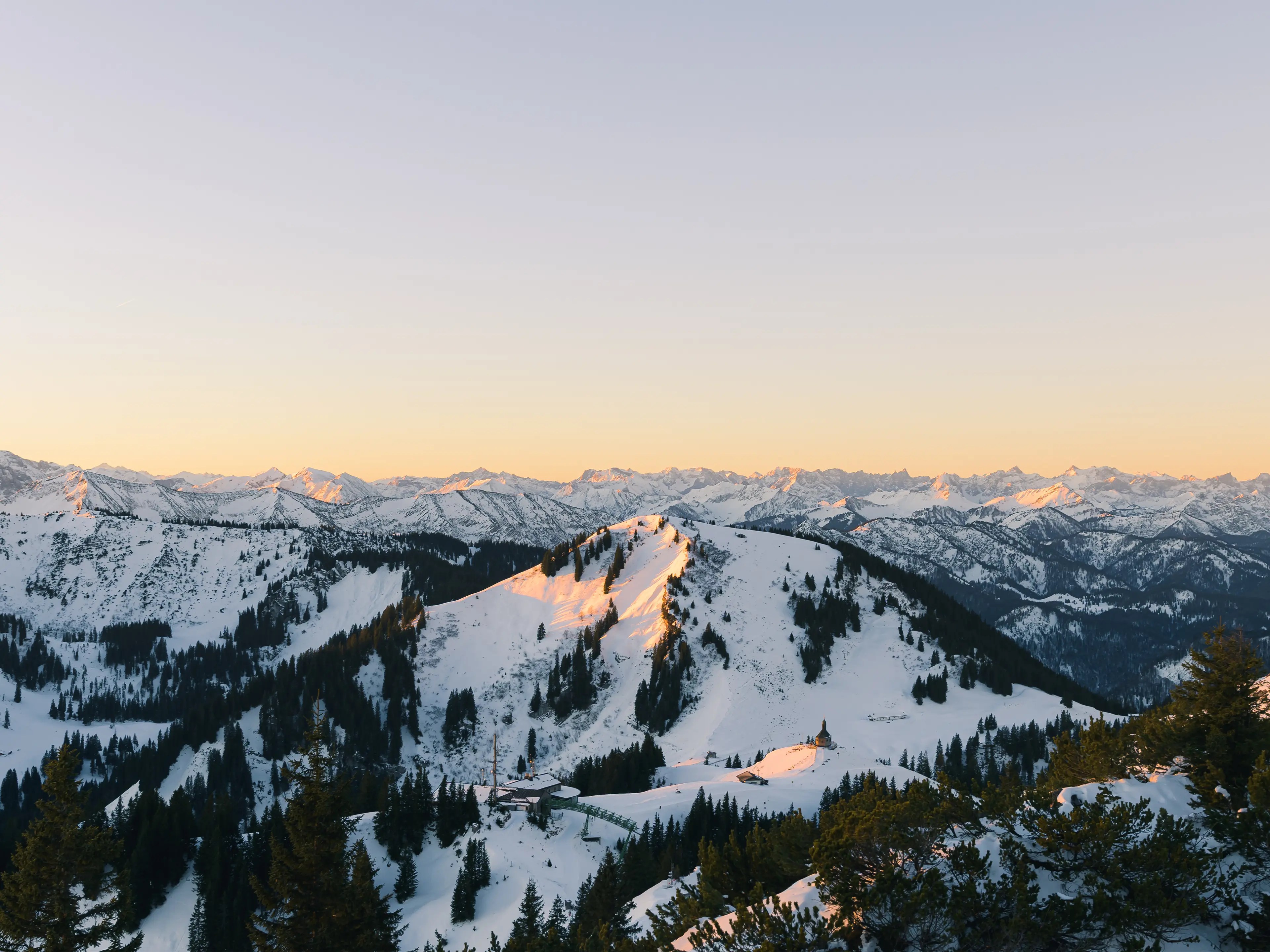 Der Blick über die markante Wallbergkapelle hin in die verschneite Berglandschaft ist besonders zum Sonnenaufgang am Wallberg grandios.