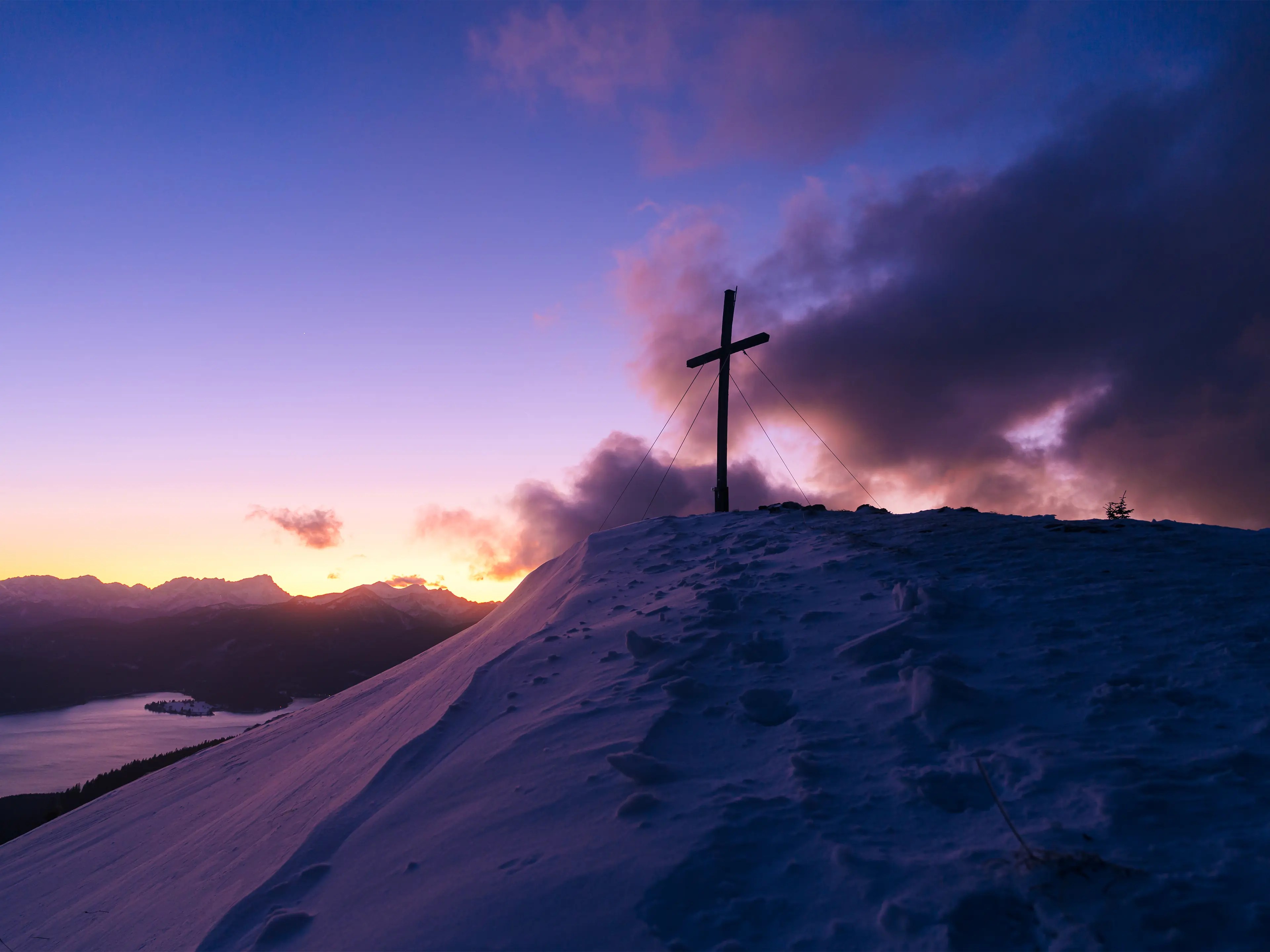 Das Gipfelkreuz zur Blauen Stunde an einem stürmischen Winterabend.