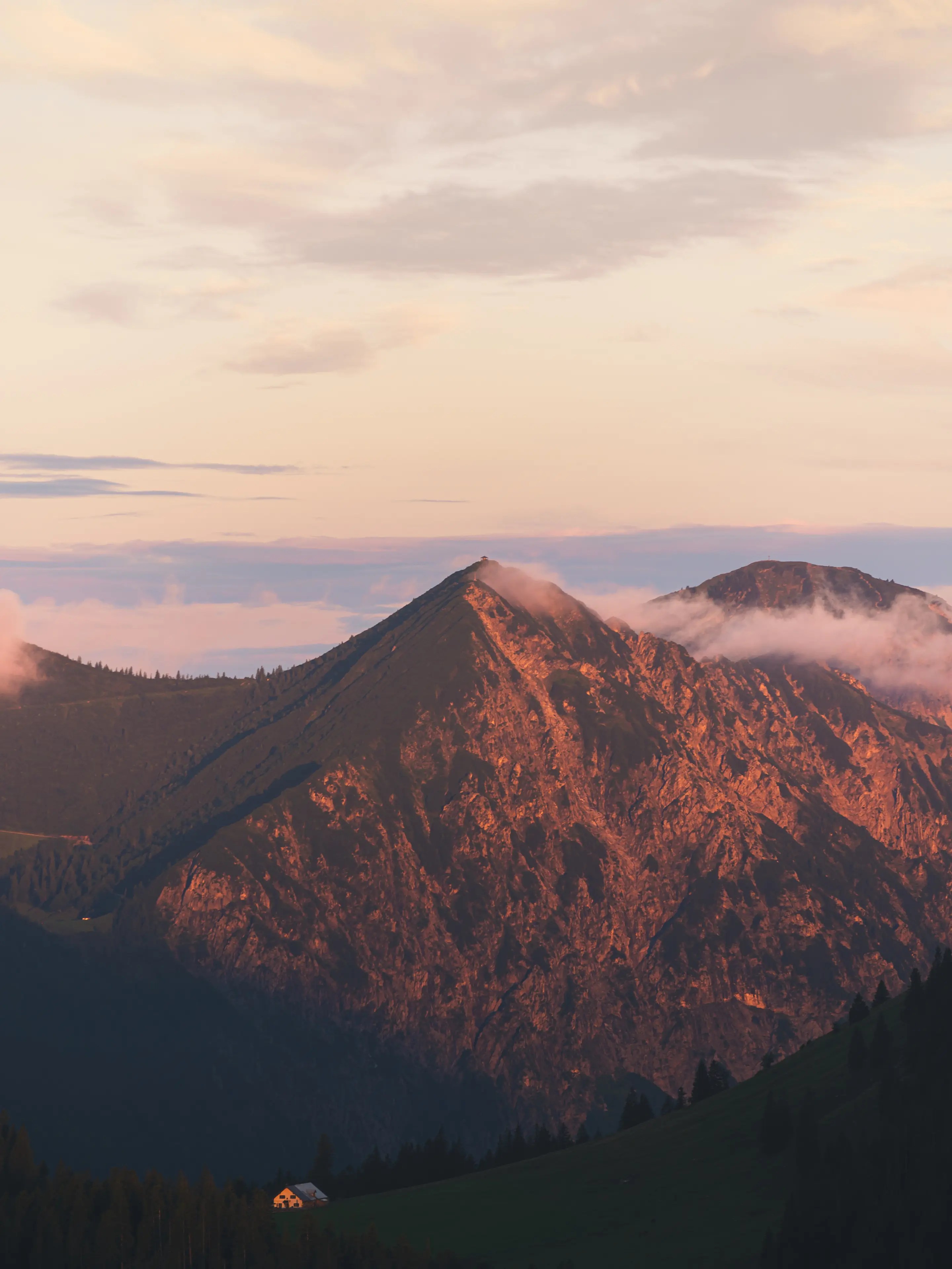 Der Herzogstand leuchtet orange im Morgenlicht. Der kleine Pavillon am Gipfel zu auch zu erkennen.
