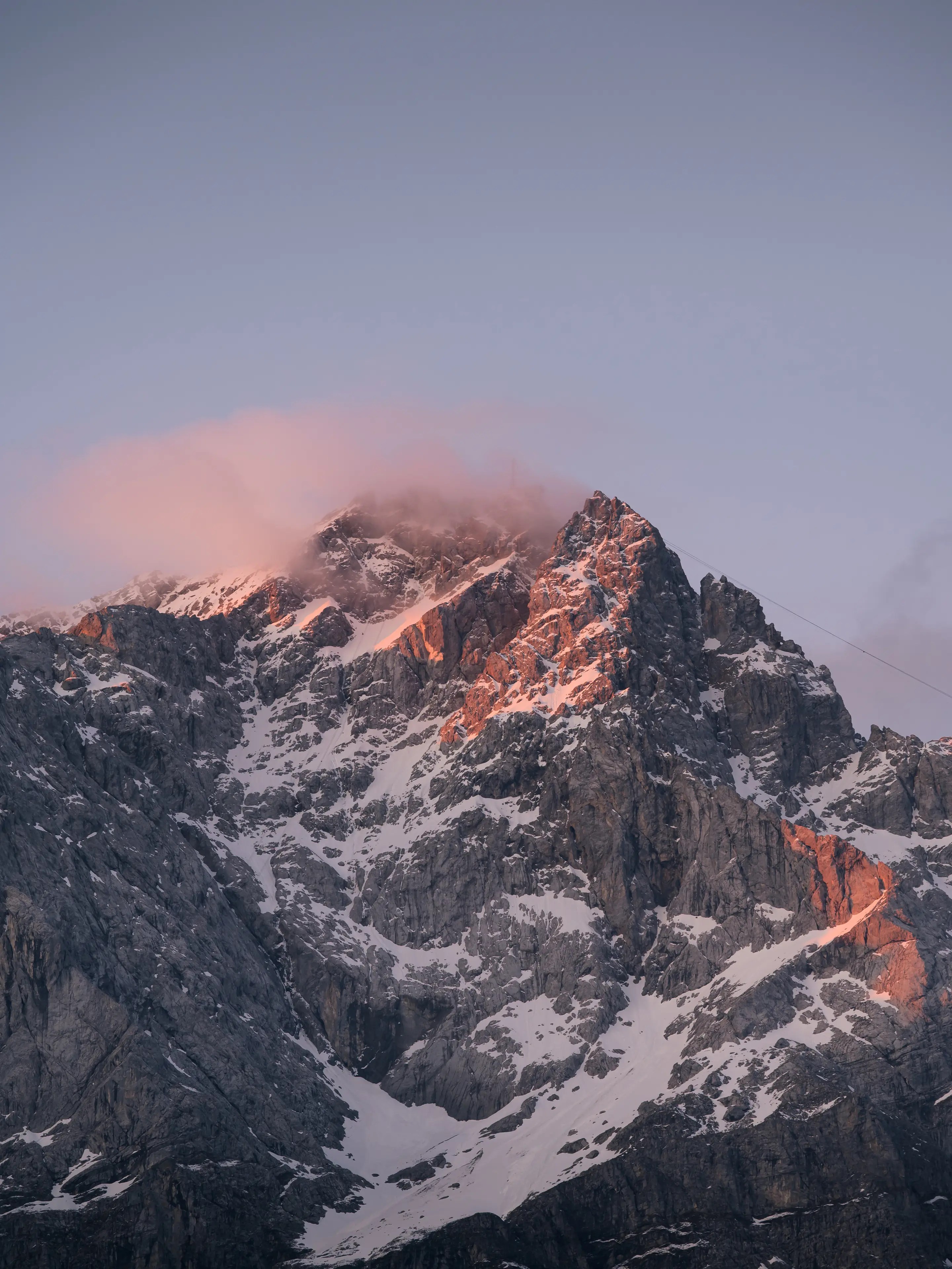 Die Zugspitze ist noch teilweise mit Schnee bedeckt und leuchtet rot zum Sonnenaufgang.