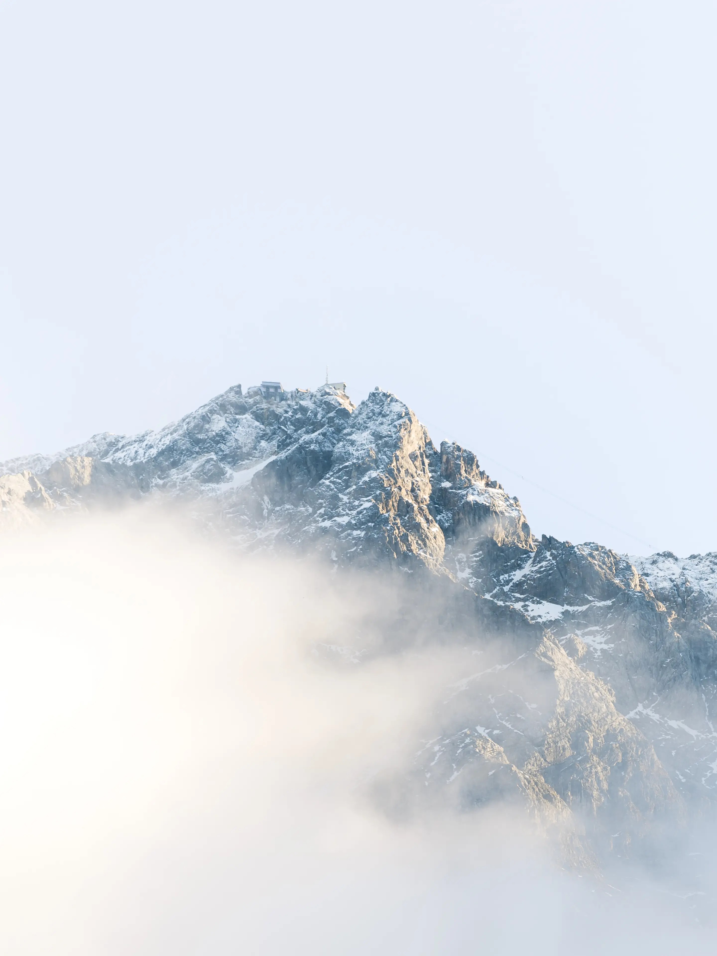 Die Zugspitze leuchtet in der Nachmittagssonne teilweise von Wolken umhüllt.