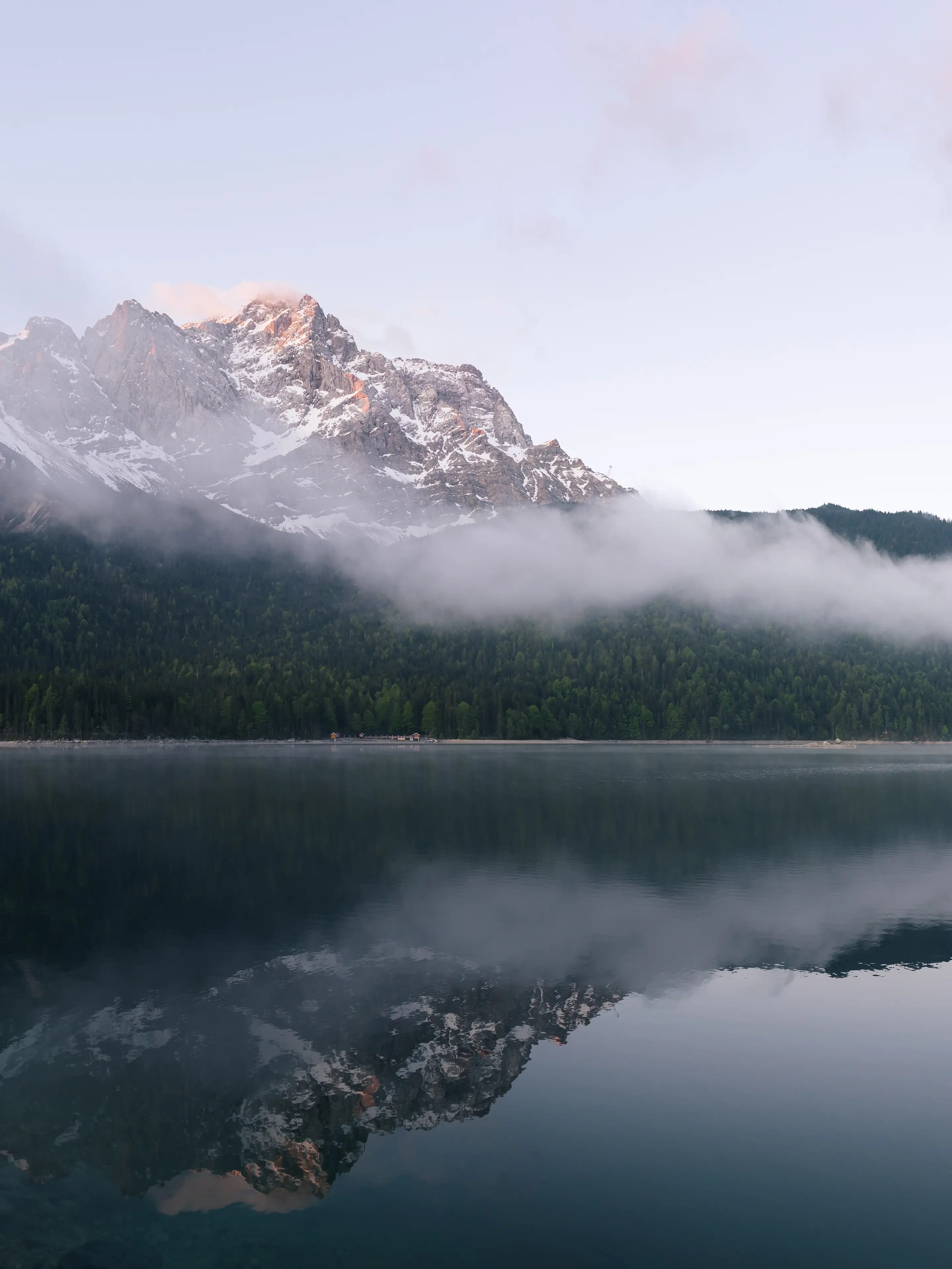 Die Zugspitze leuchtet im Morgenlicht und spiegelt sich im Eibsee.