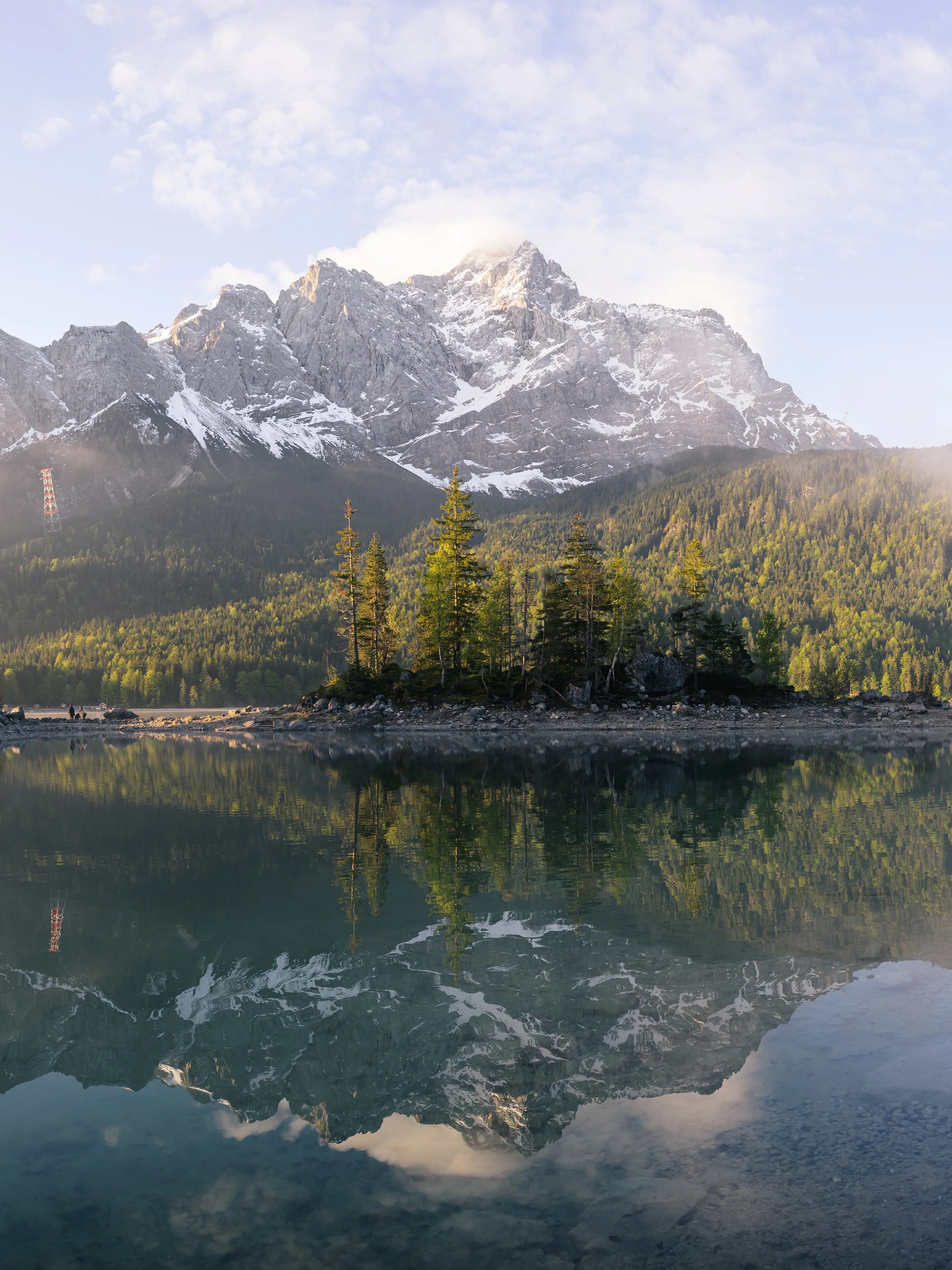 Die Zugspitze spiegelt sich im Eibsee am Himmel sind Schönwetterwolken.