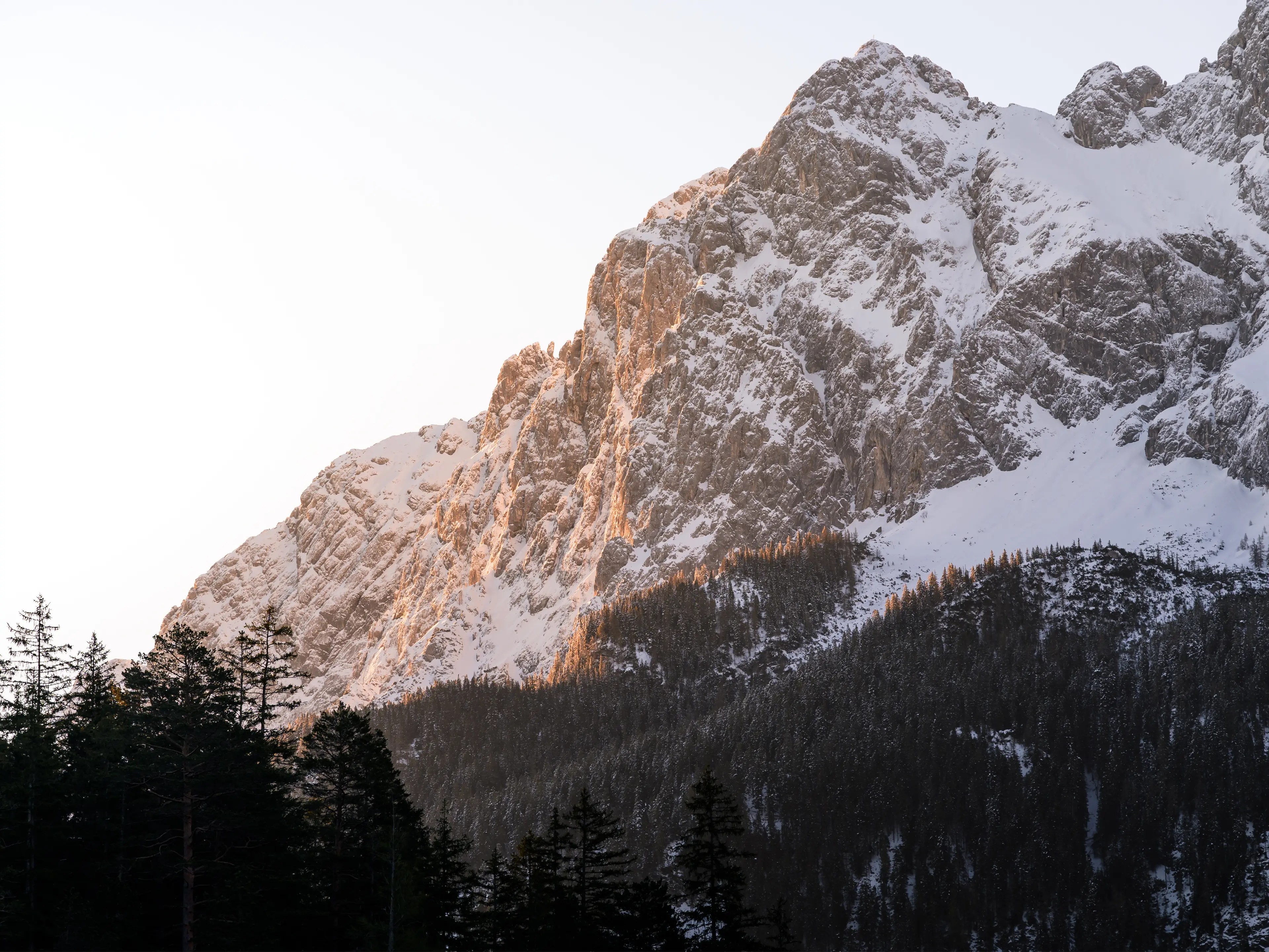 Mit Schnee bedeckte Berge leuchten orange in der Morgensonne.