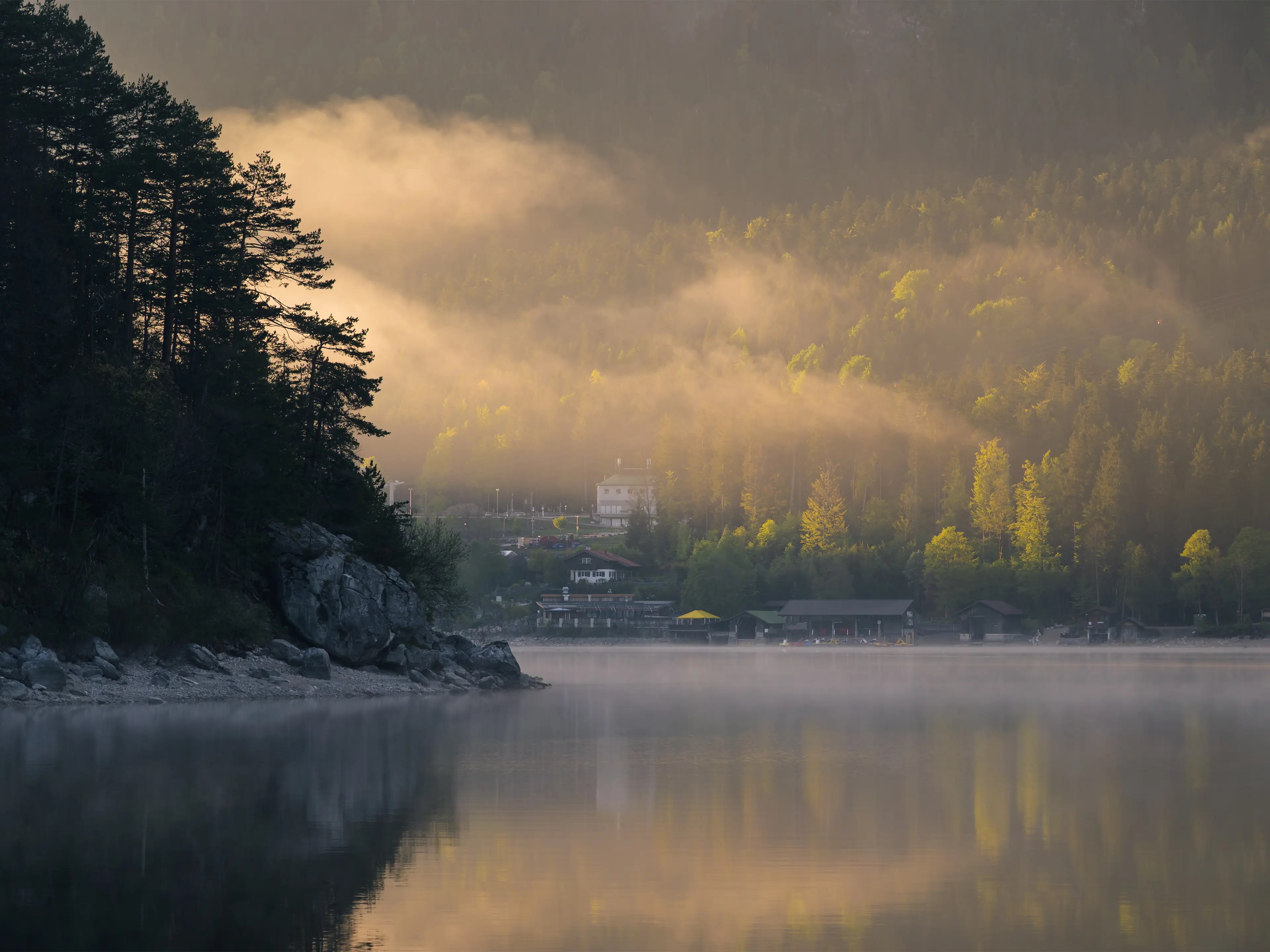 Blick über den Eibsee zum anderen Ufer an dem Gebäude stehen.