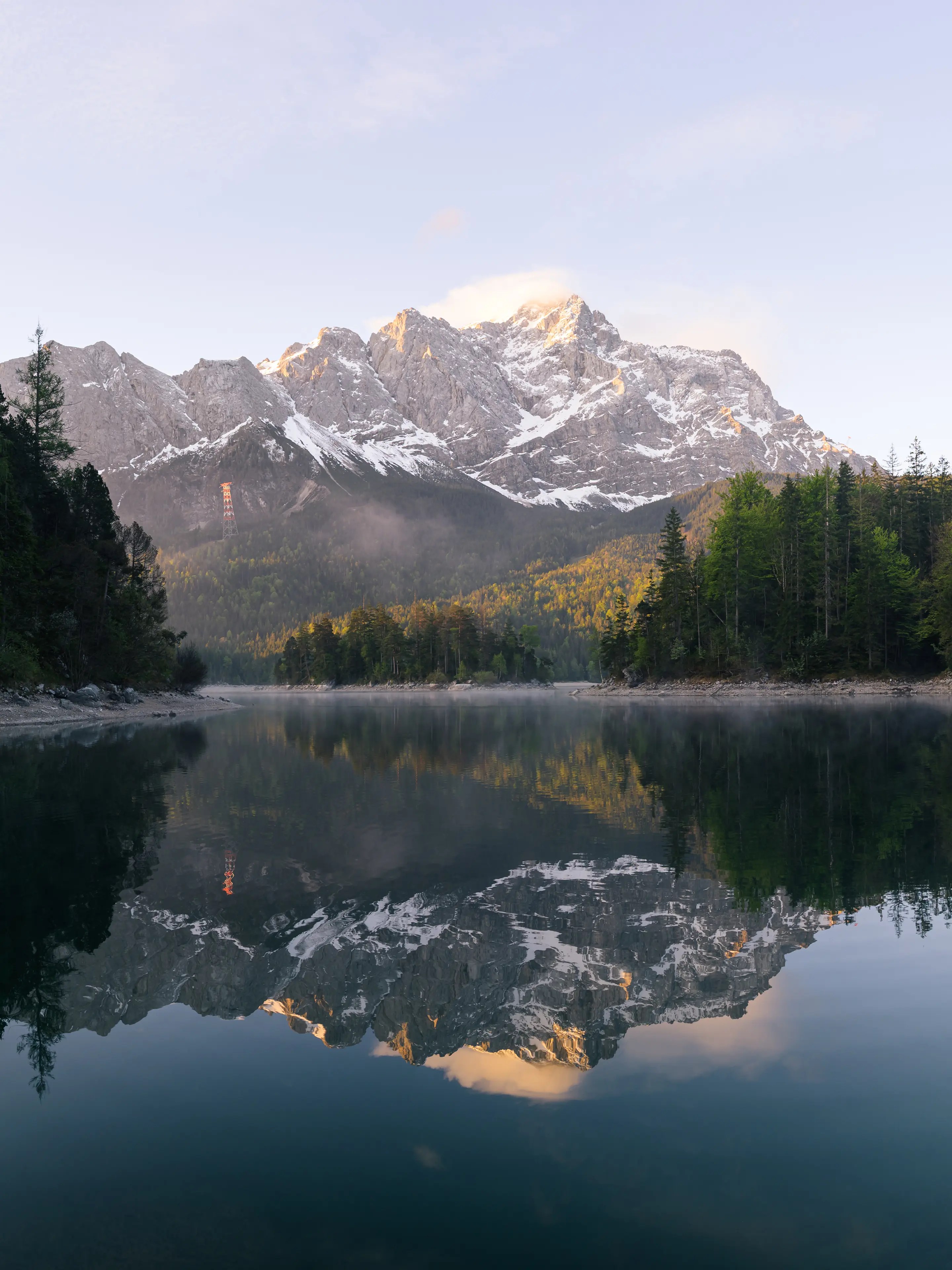 Die Zugspitze leuchtet im Mogenlicht und spiegelt sich im Eibsee. 