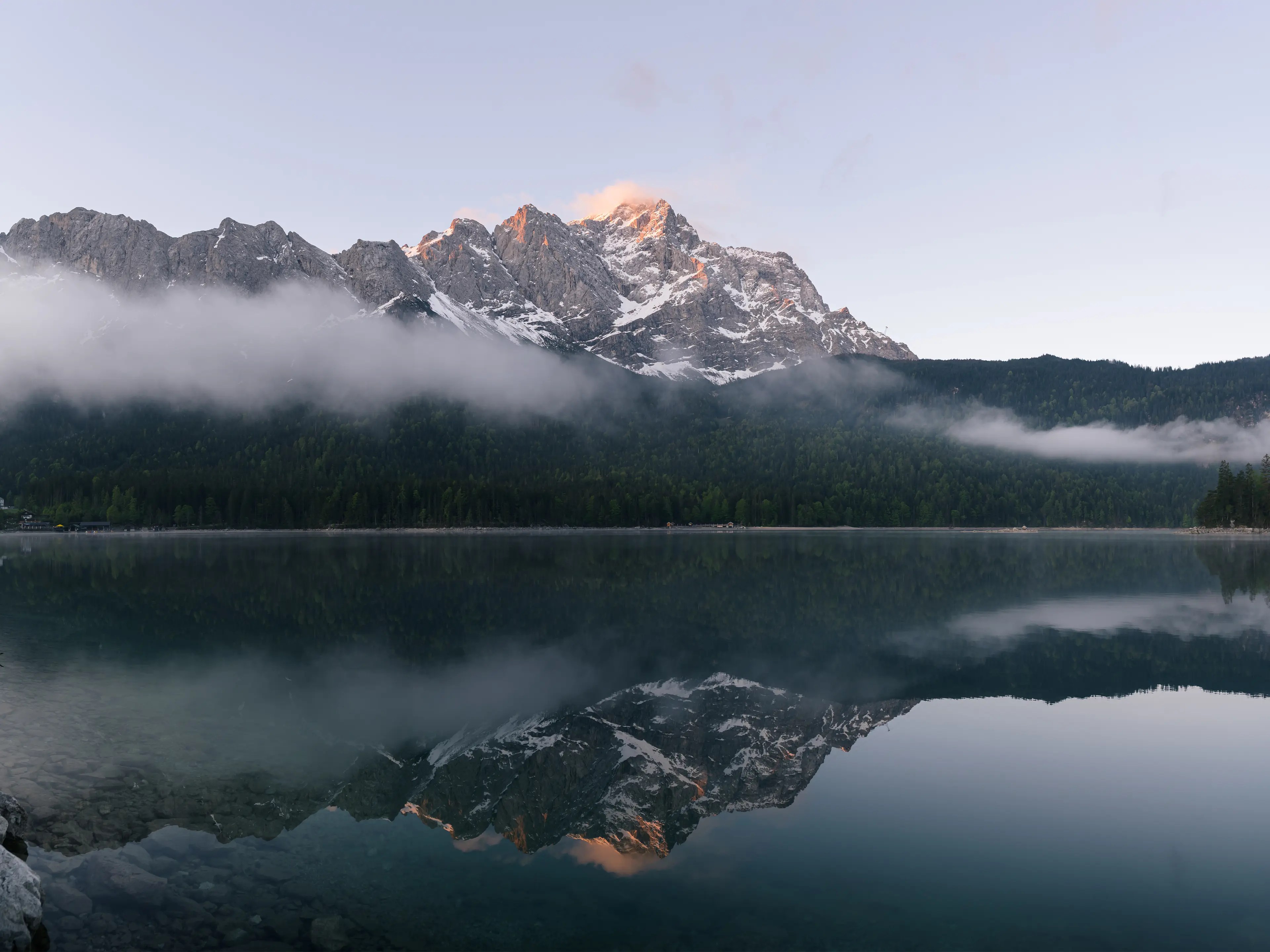 Die Zugspitze leuchtet im Morgenlicht und spiegelt sich im Eibsee.