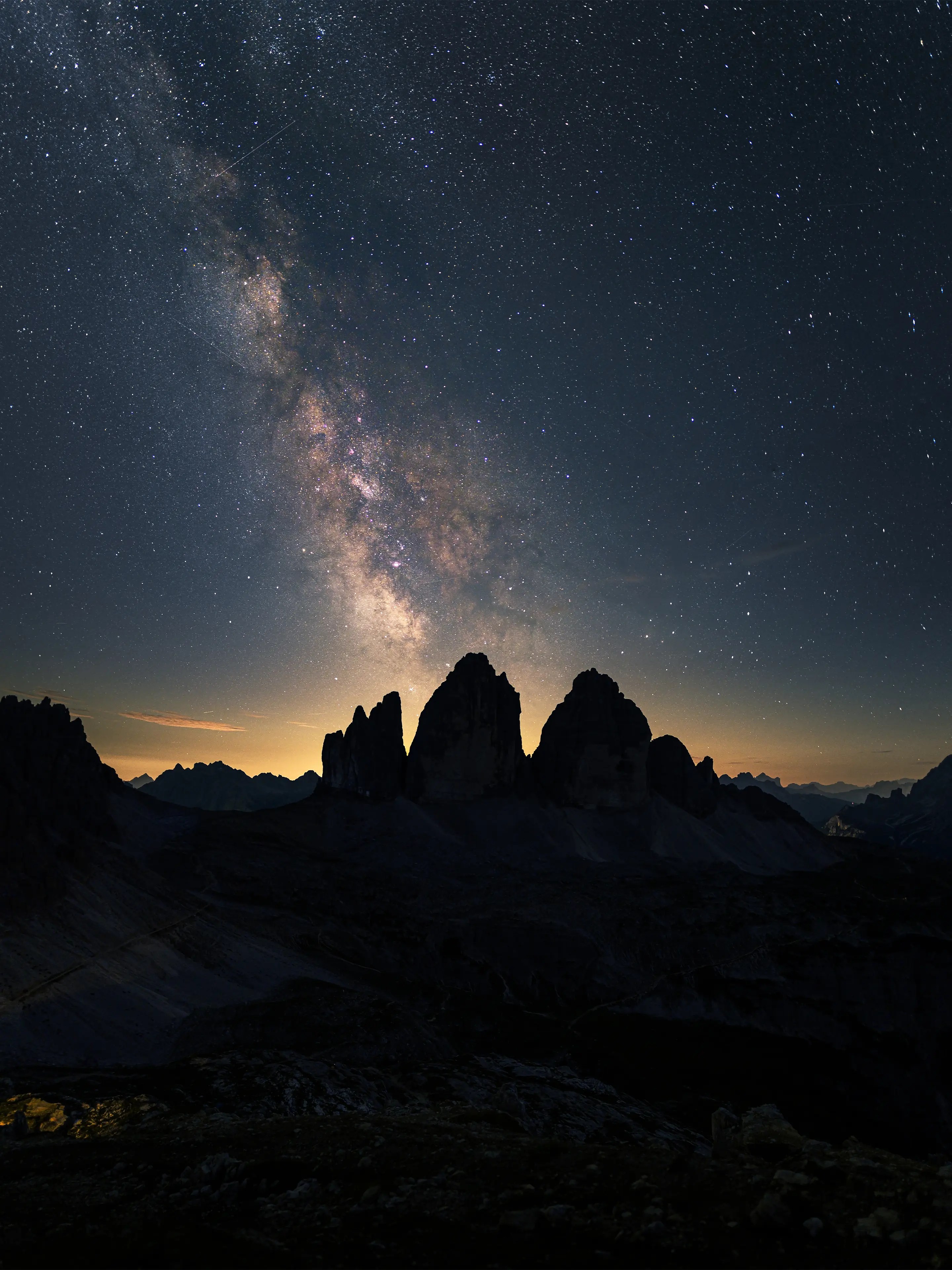 Ein vertikales Panorama der Milchstraße über den Drei Zinnen.