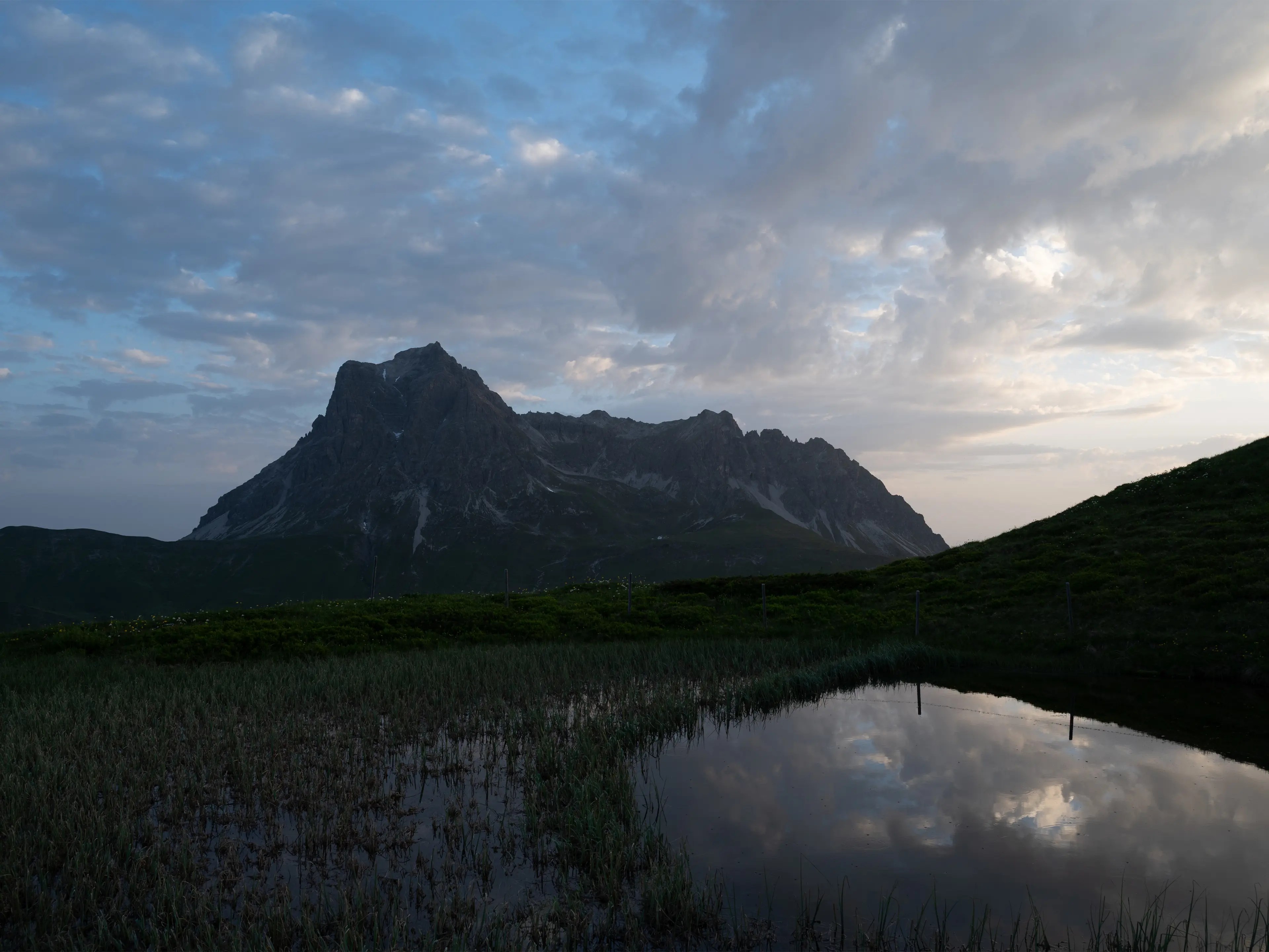 Eine Berglandschaft im Morgenlicht, im Vordergrund ist ein See