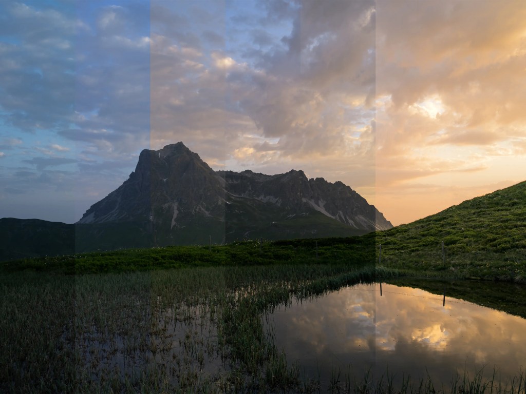 Eine Berglandschaft im Morgenlicht, im Vordergrund ist ein See