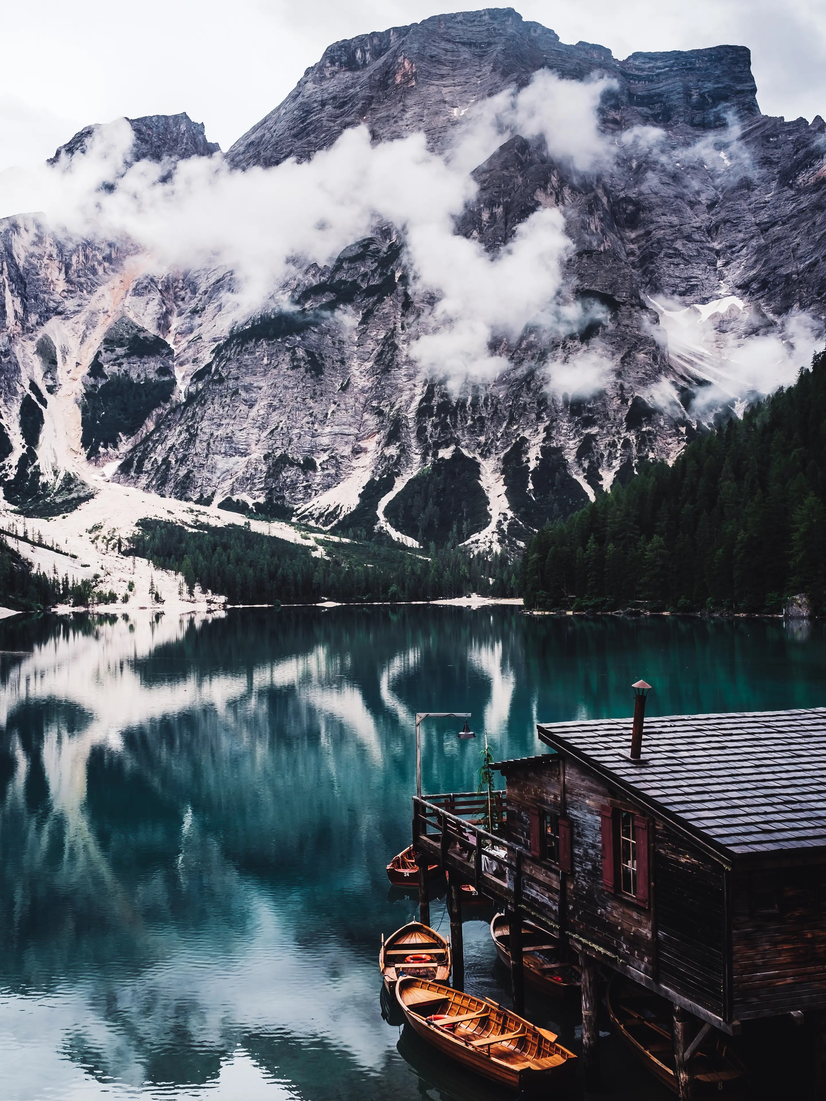 Der Pragser Wildsee mit der Holzhütte des Bootsverleihs und den Dolomiten im Hintergrund.
