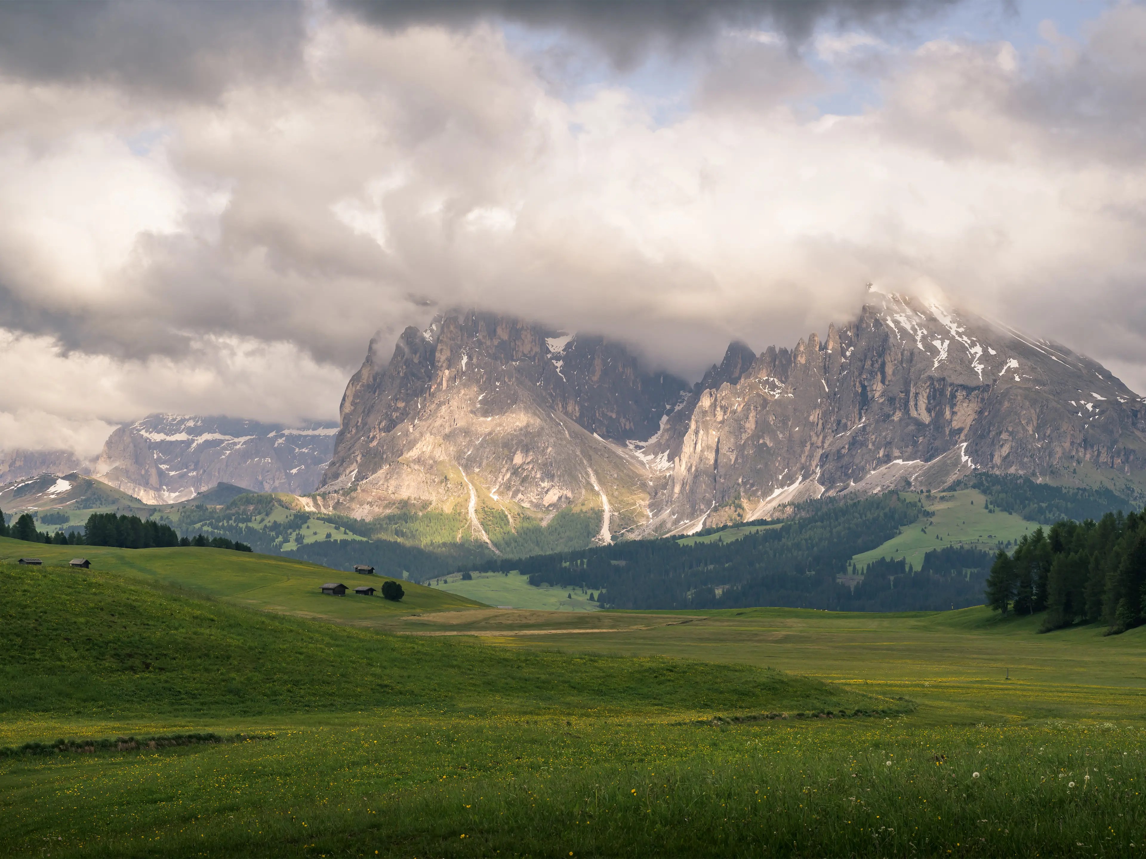 Lang- und Plattkofel mit wolkenverhangenen Gipfel und den Wiesen der Seiser Alm.