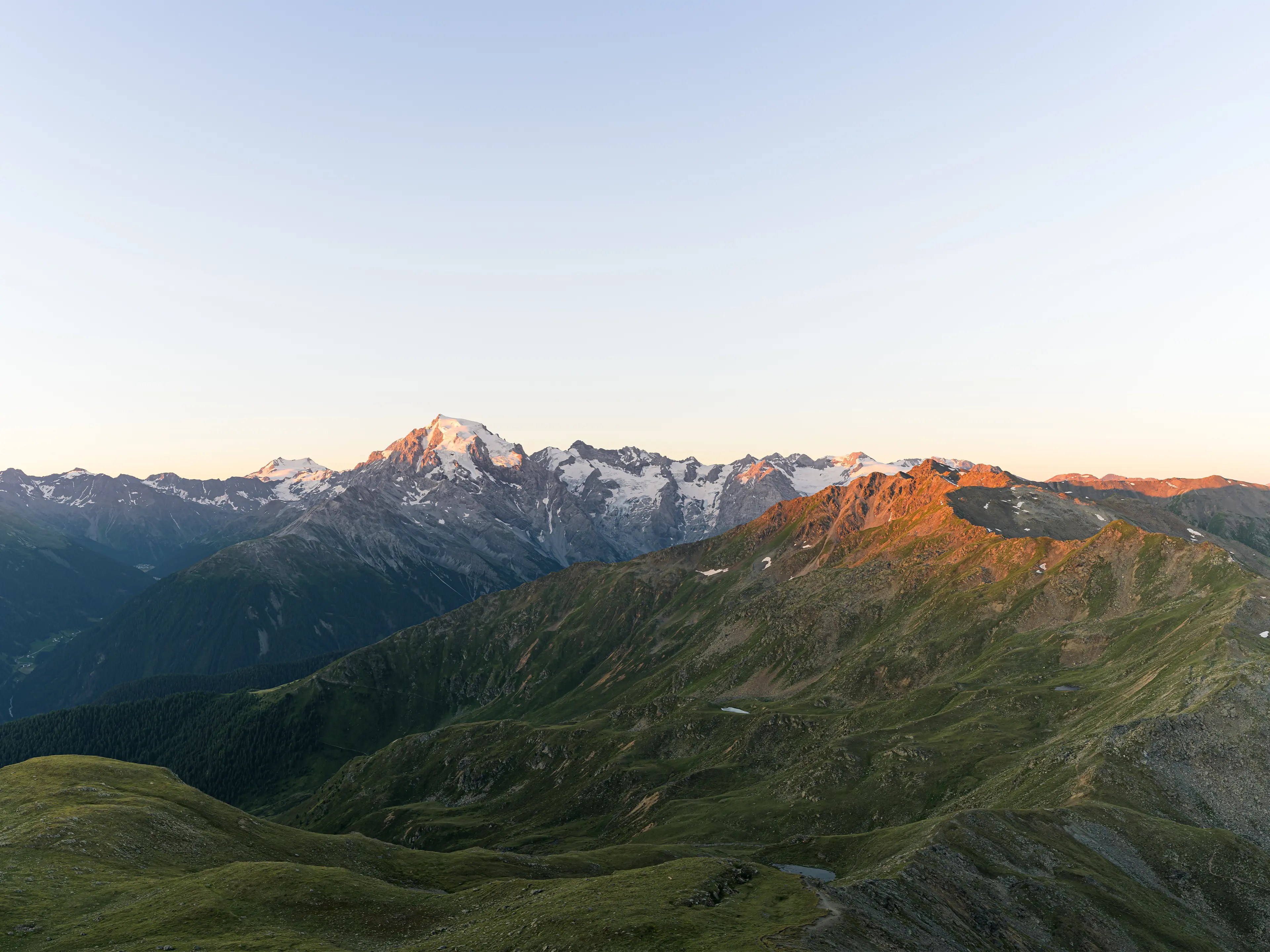 Sonnenaufgang am Piz Chavalatisch. Der Ortler und die umliegenden Gipfel leuchten in der Morgensonne.