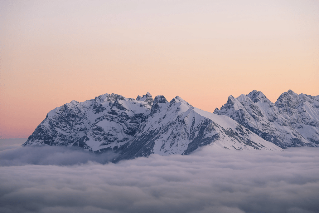 Eine winterliche Berglandschaft im Morgenlicht mit einer dichten Nebeldecke