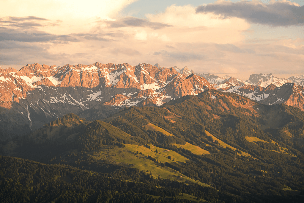 Eine Berglandschaft im Frühling im warmen Licht. Die Berge leuchte Orange bedeckt mit den letzten Schneeresten.