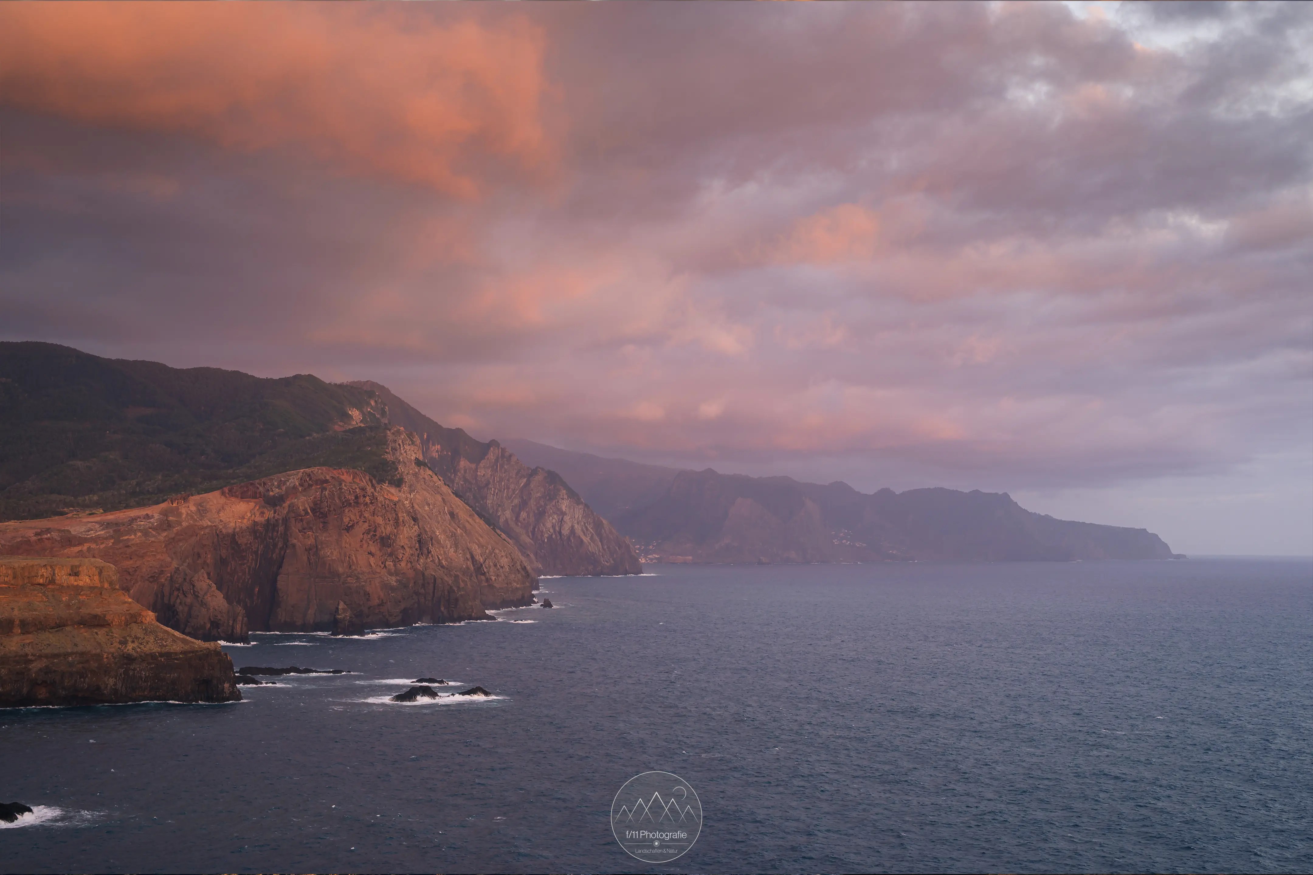 Die steile Küste Madeira in einem kräftigen orangen Morgenlicht.