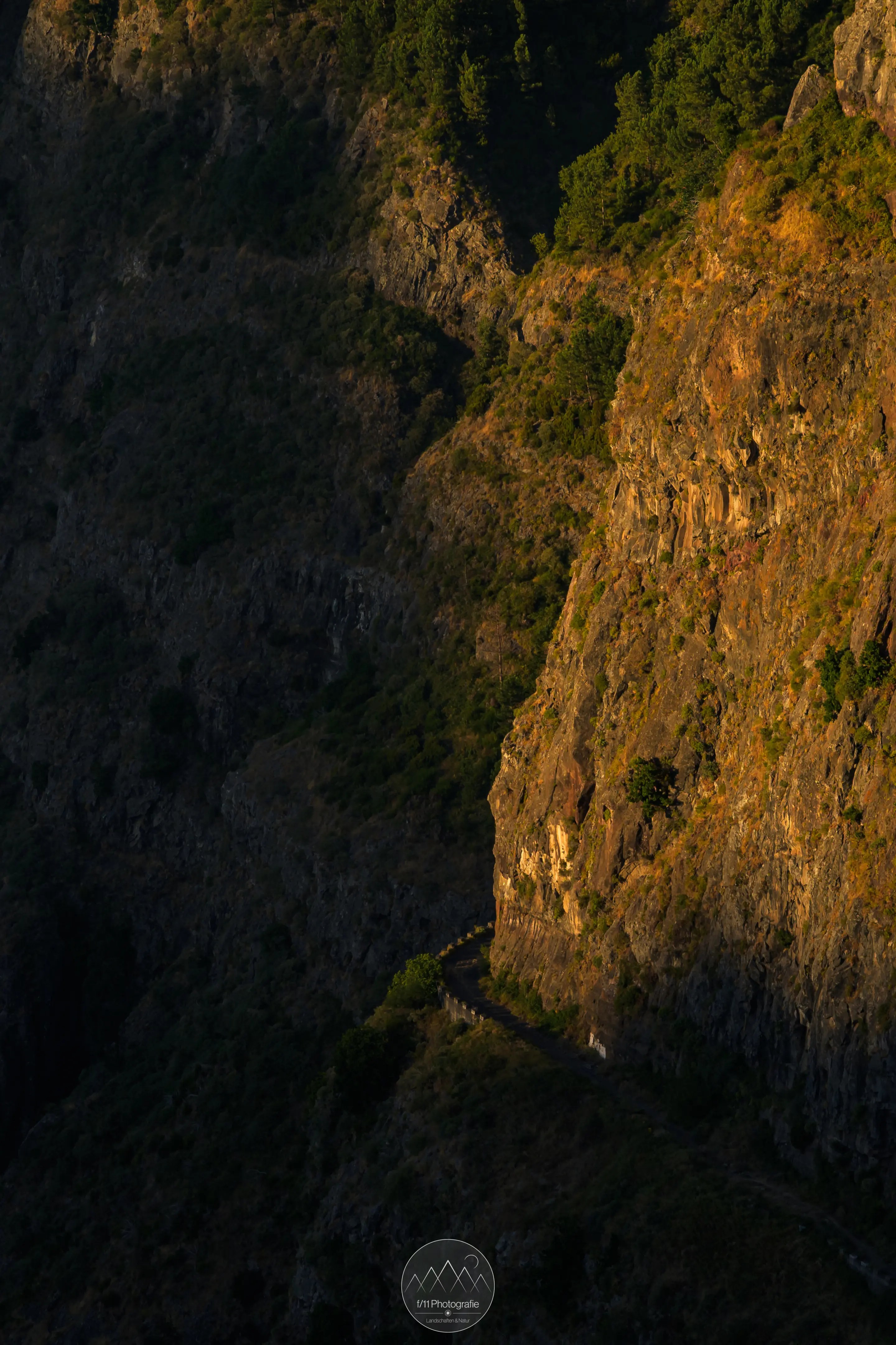 Eine alte Straße im Abendlicht an einer steilen Felswand.