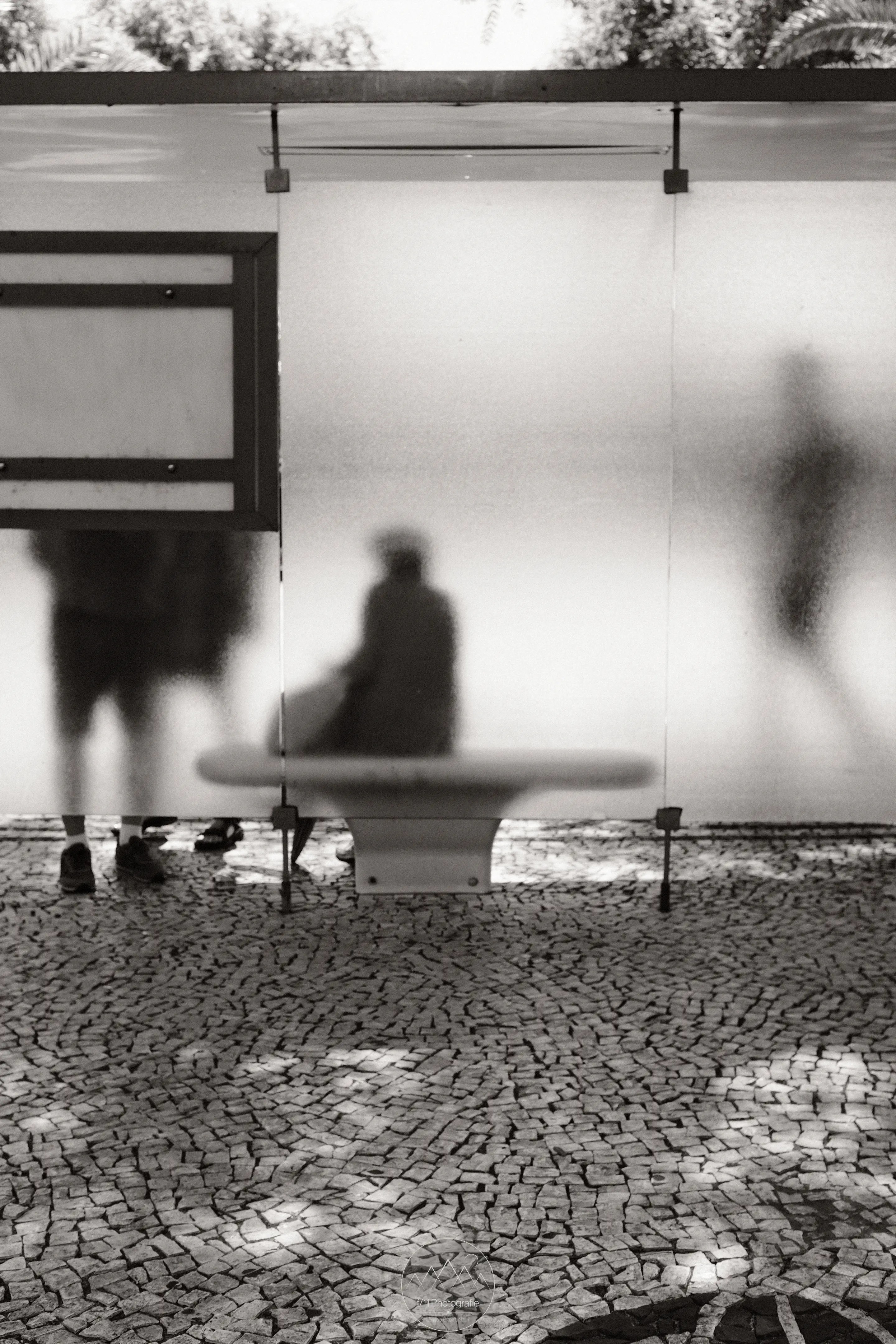 Die Silhouette einer Frau, die an einer Bushaltestelle sitzt.