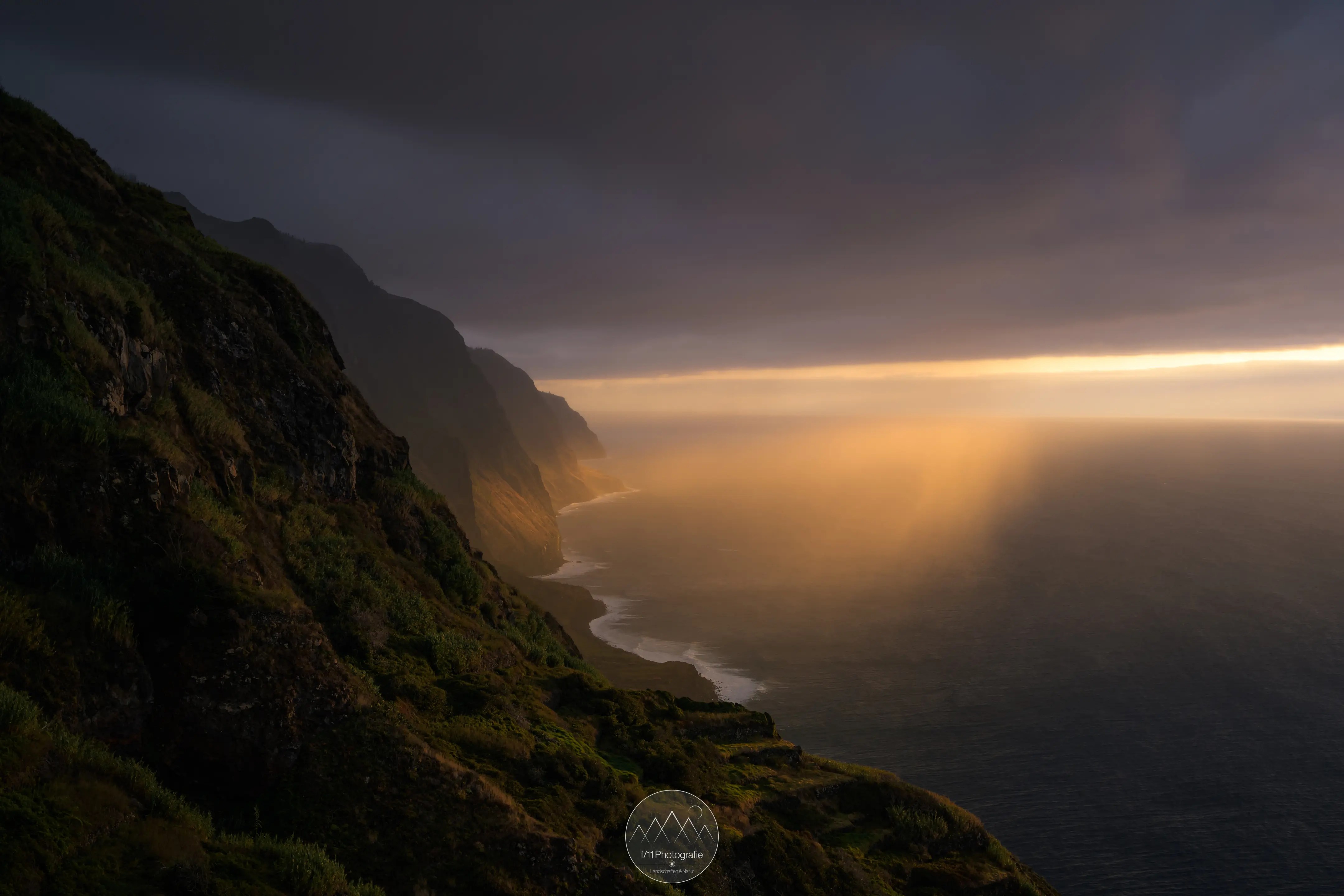 Einmalige Stimmung am Miradouro Ponta da Ladiera. Die Sonne schien durch eine Wolkenlücke während ein kleiner Regenschauer an den Klippen entlang zog.