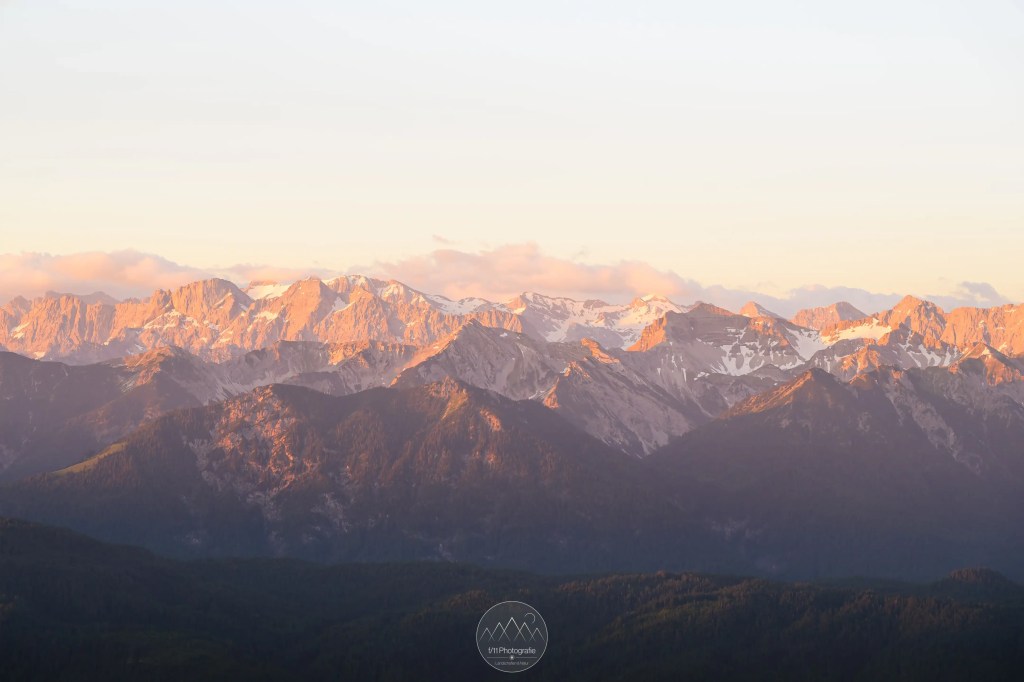 Der Ausblick zum Sonnenaufgang am Herzogstand in Richtung der Morgenlicht glühenden Gipfel des Karwendelgebirges.