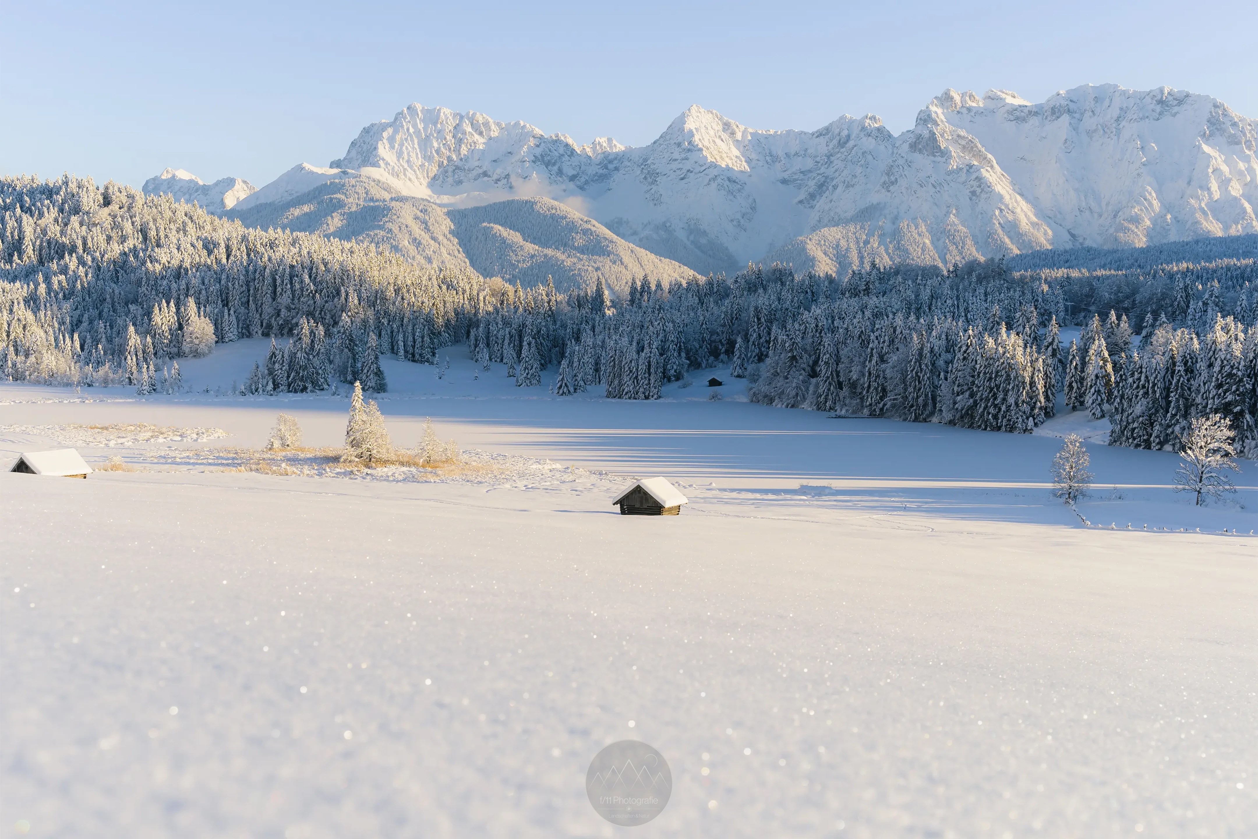 Der Blick über die schneebedeckten Wiesen und über den Geroldsee zum verschneiten Karwendelgebirge in der Licht der Nachmittagssonne.