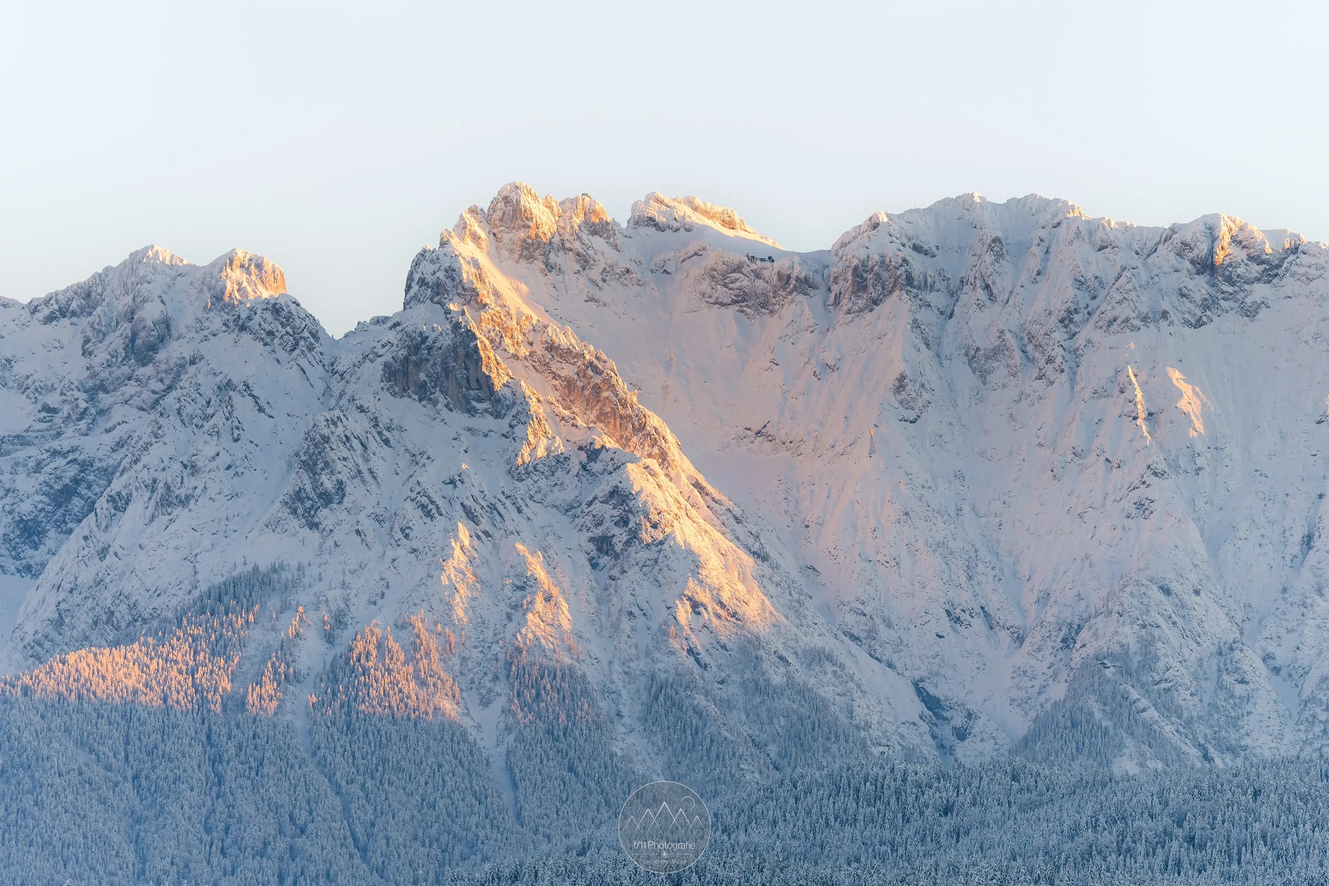 Zum Sonnenuntergang beginnen die verschneiten Berge zu Glühen.