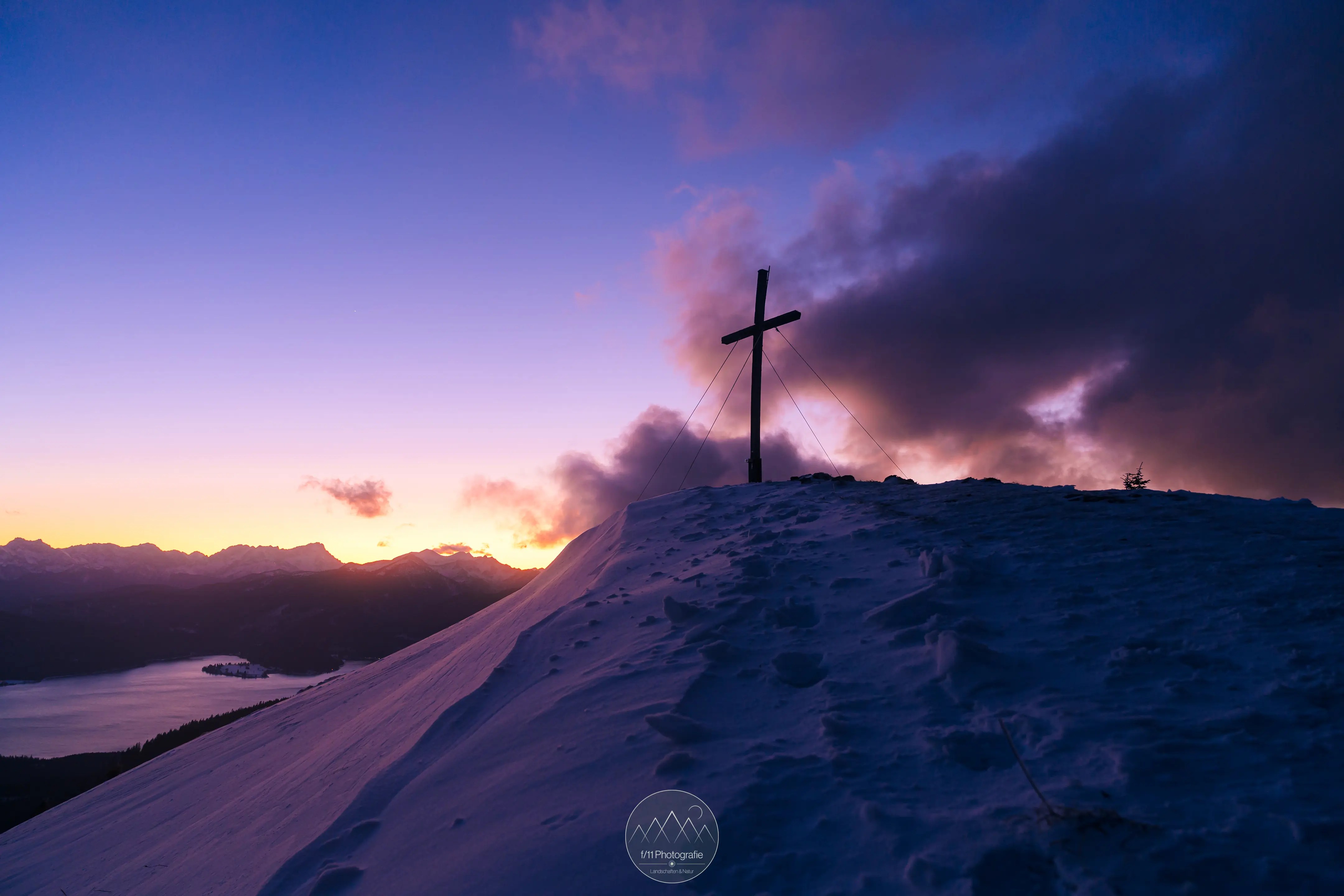 Das Gipfelkreuz zur Blauen Stunde an einem stürmischen Winterabend.