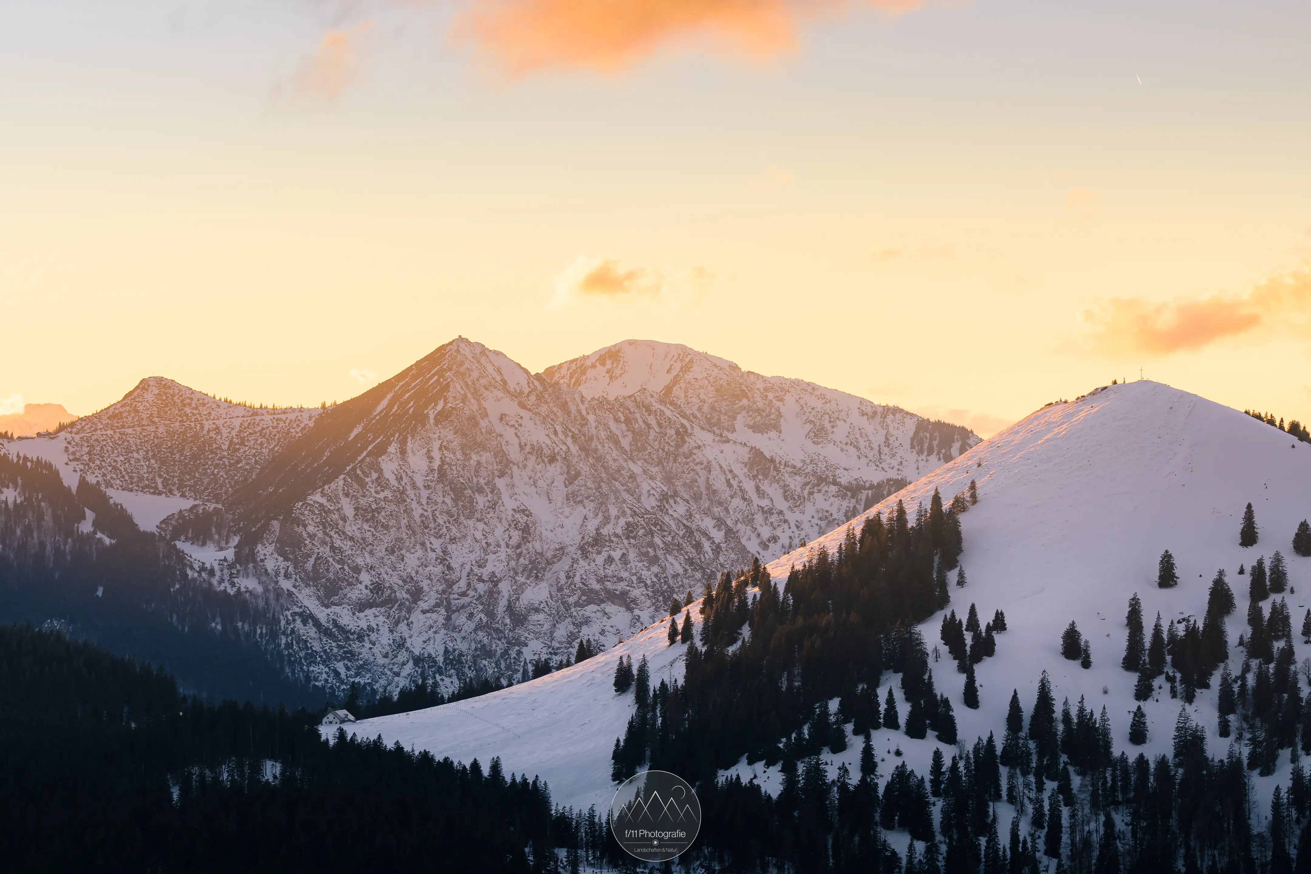 Jochberg und Herzogstand bedeckt mit Schnee zum Sonnenuntergang.