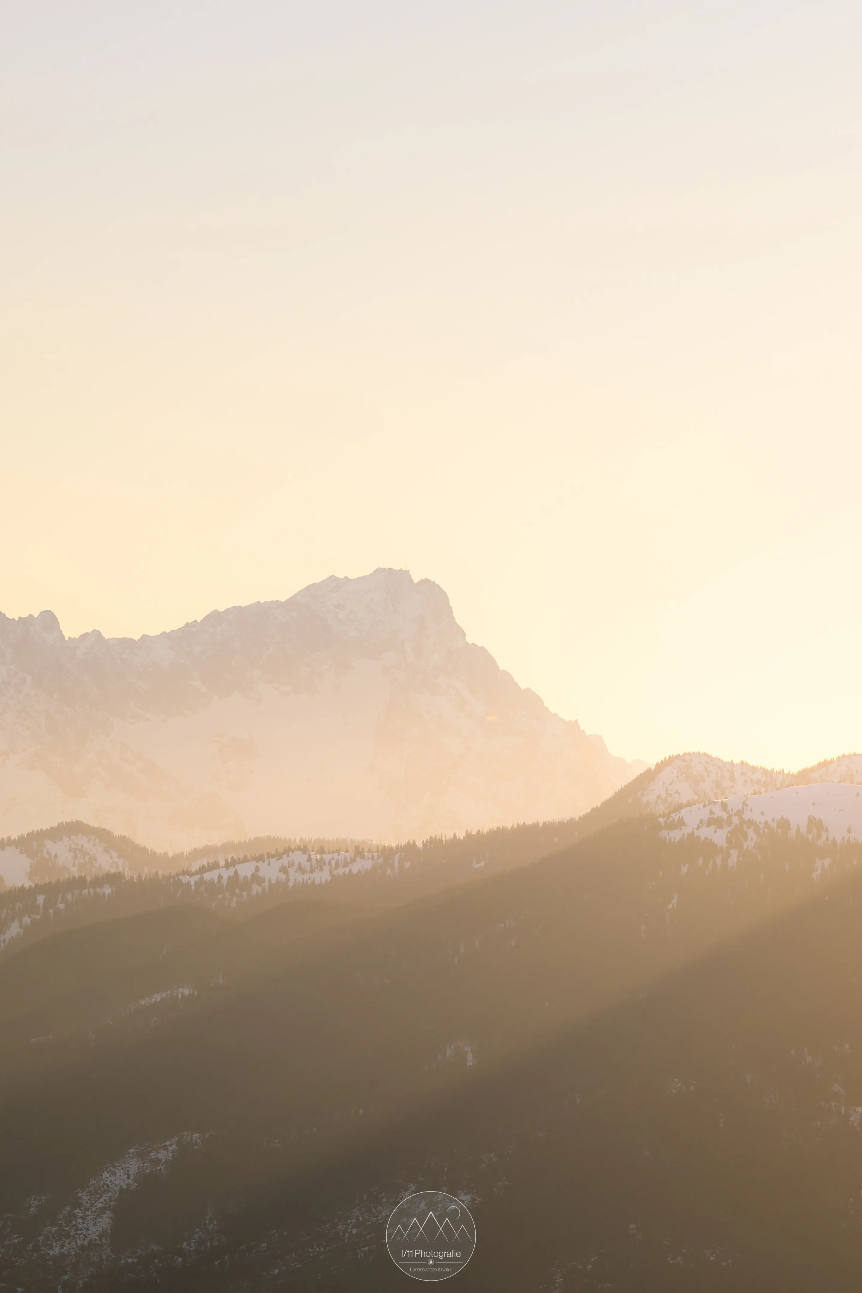 Die Zugspitze und die umliegende Landschaft leuchten im goldenen Abendlicht.