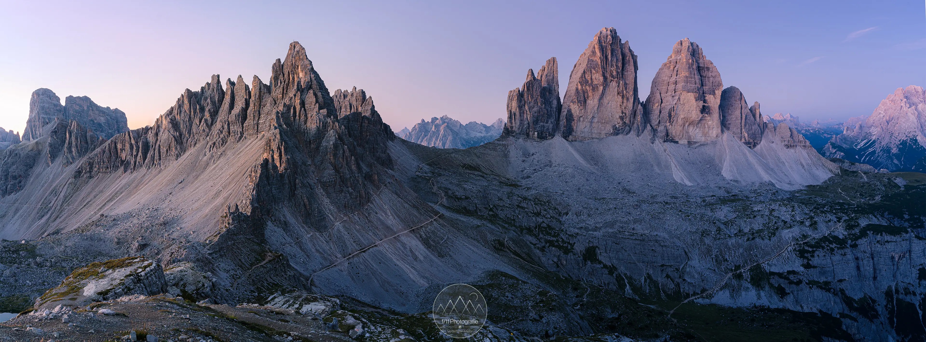 Panoramablick auf den Drei Zinnen und den Paternkofel zur blauen Stunde.