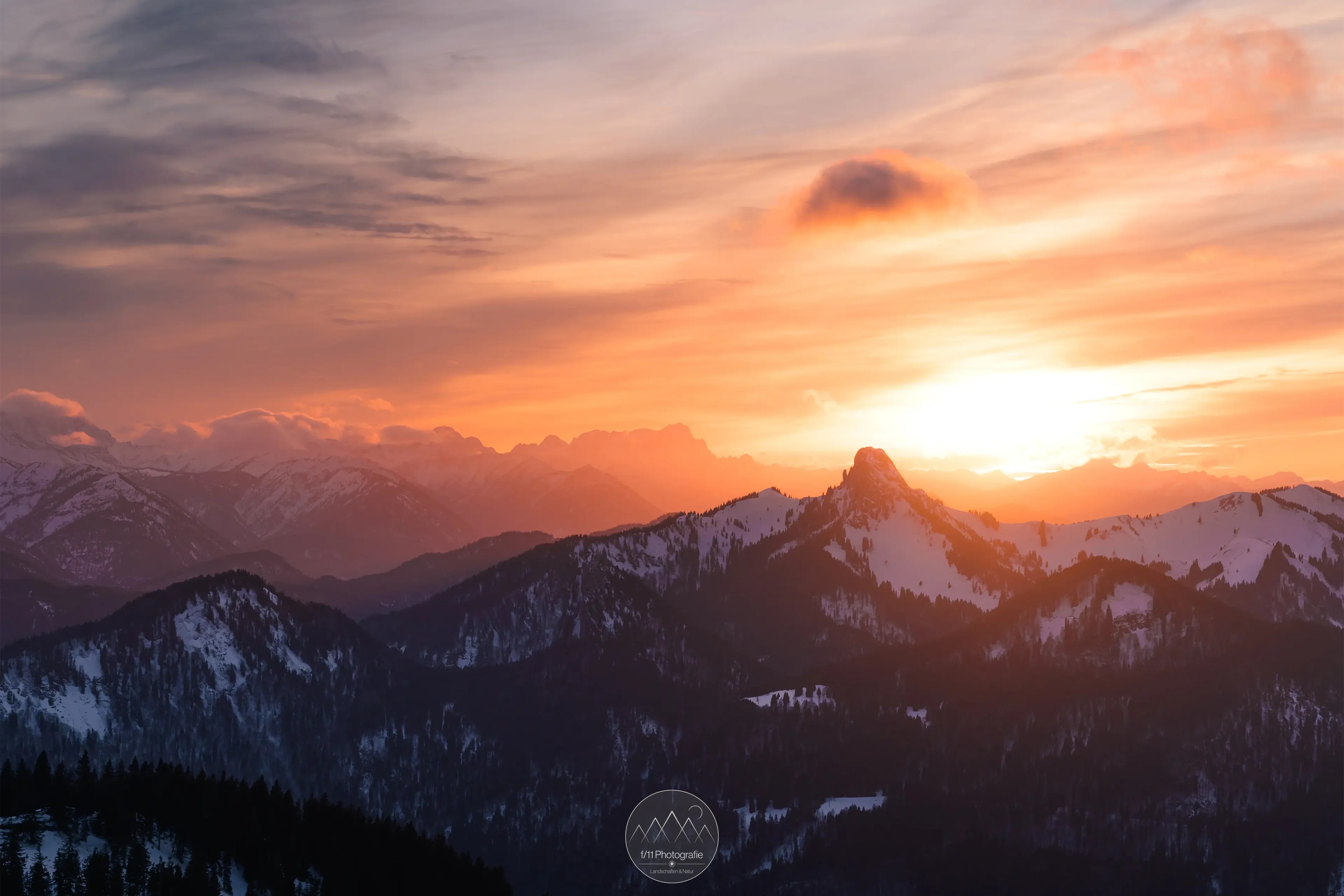 Der Ausblick von der Wallbergkapelle in Richtung Zugspitze. Rechts im Vordergrund sind der Ross- und Buchstein zu erkennen. Das Bild entstand ausnahmsweise zum Sonnenuntergang und nicht zum Sonnenaufgang.