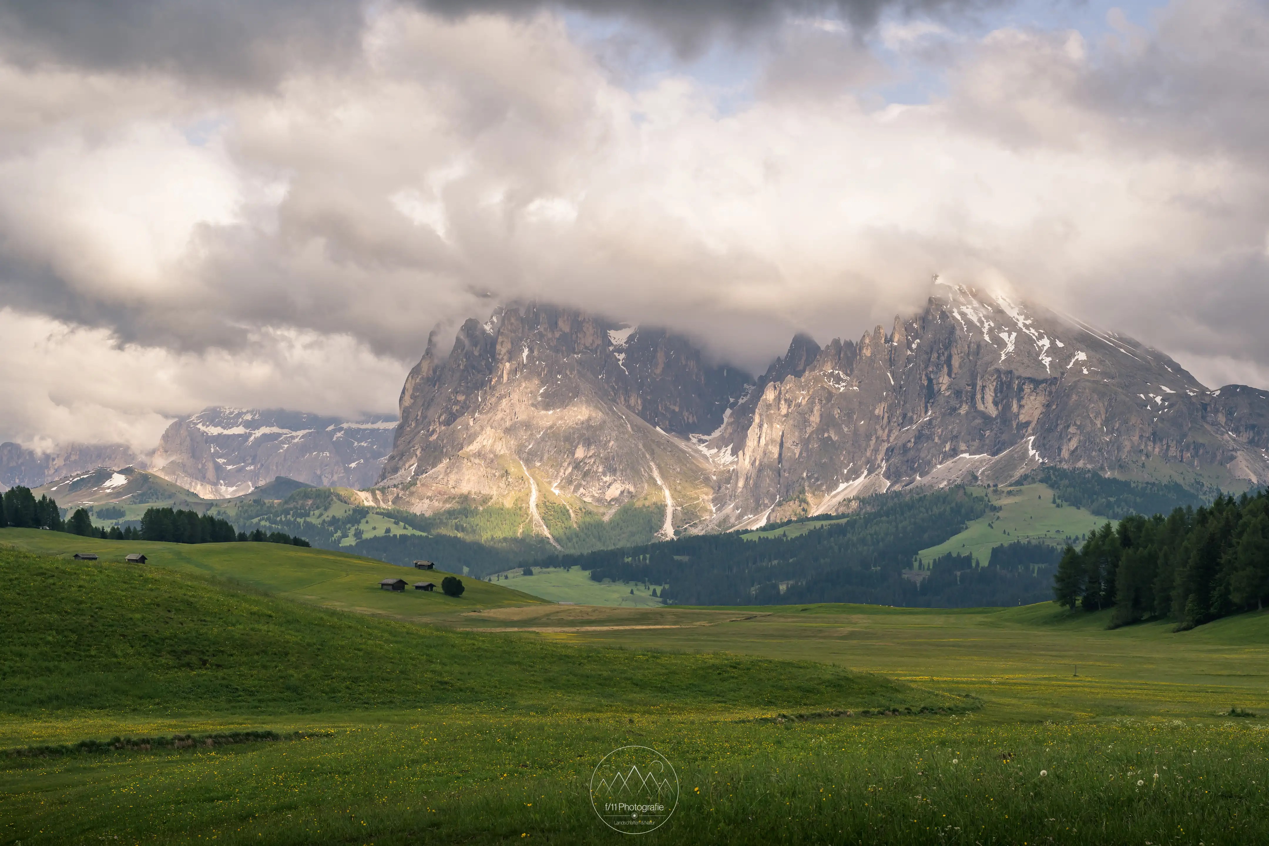 Lang- und Plattkofel mit wolkenverhangenen Gipfel und den Wiesen der Seiser Alm.
