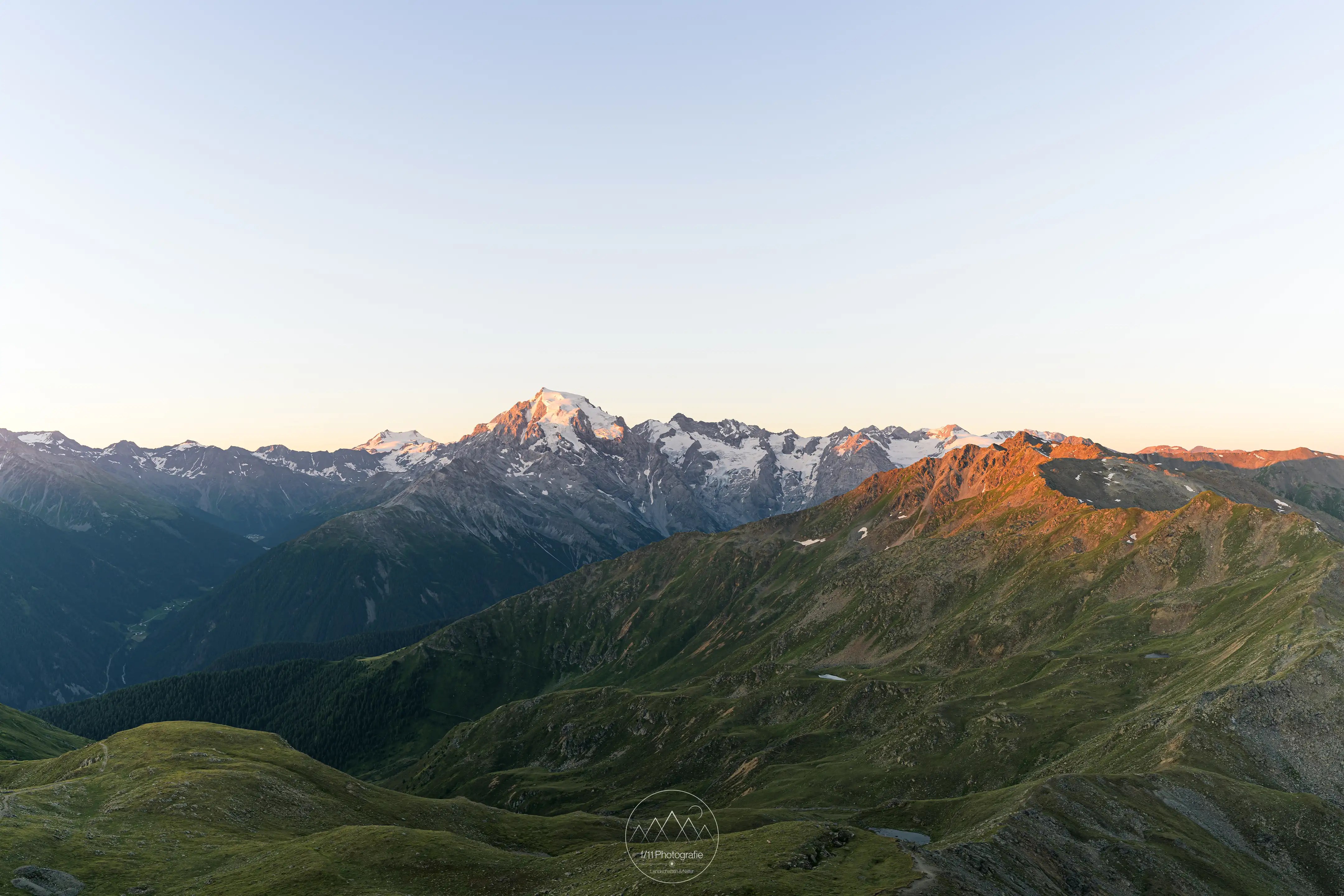 Sonnenaufgang am Piz Chavalatisch. Der Ortler und die umliegenden Gipfel leuchten in der Morgensonne.