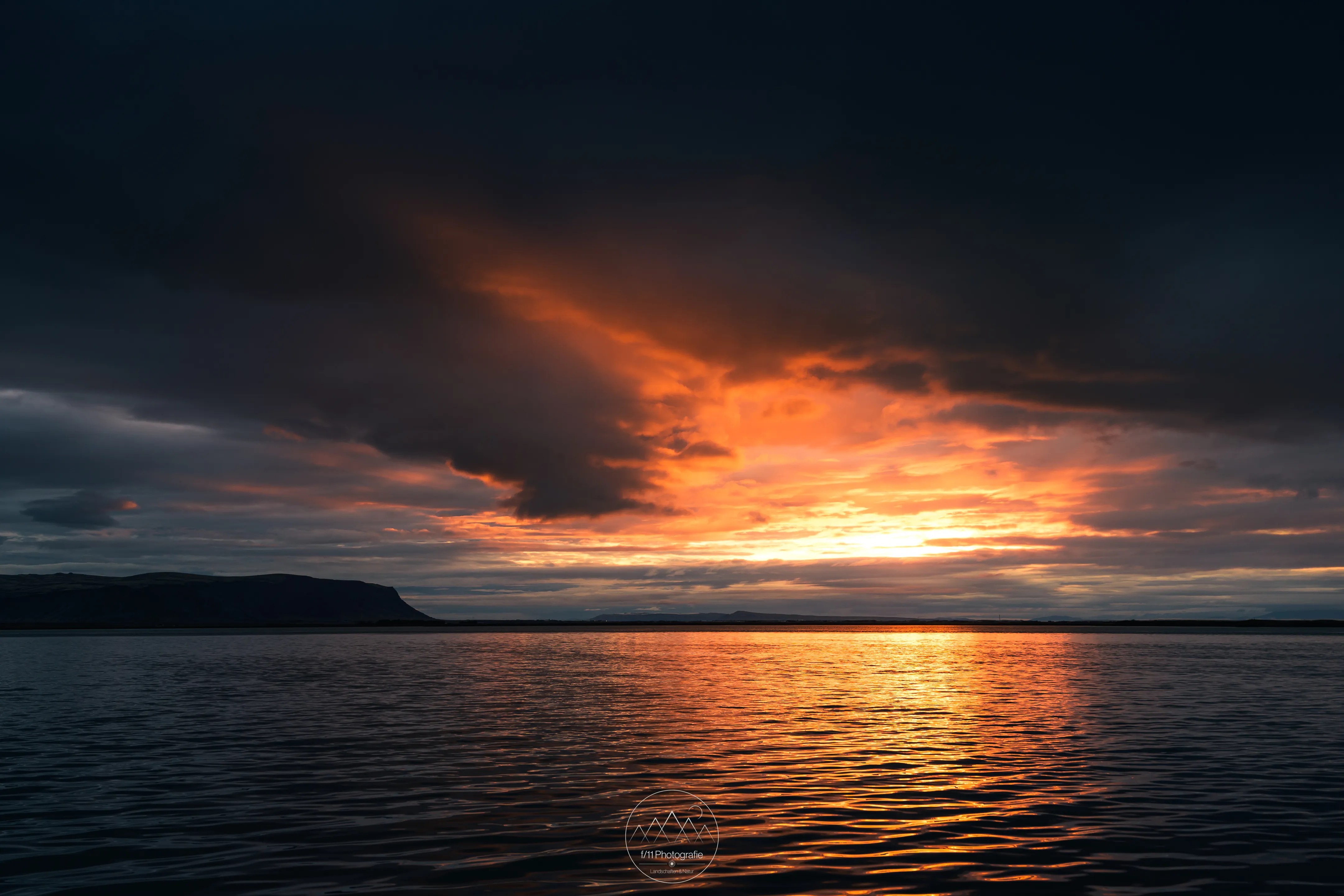 Kurz brach die Sonne durch die Wolken bei diesem Sonnenaufgang an der Bucht bei Eyrarbakki.
