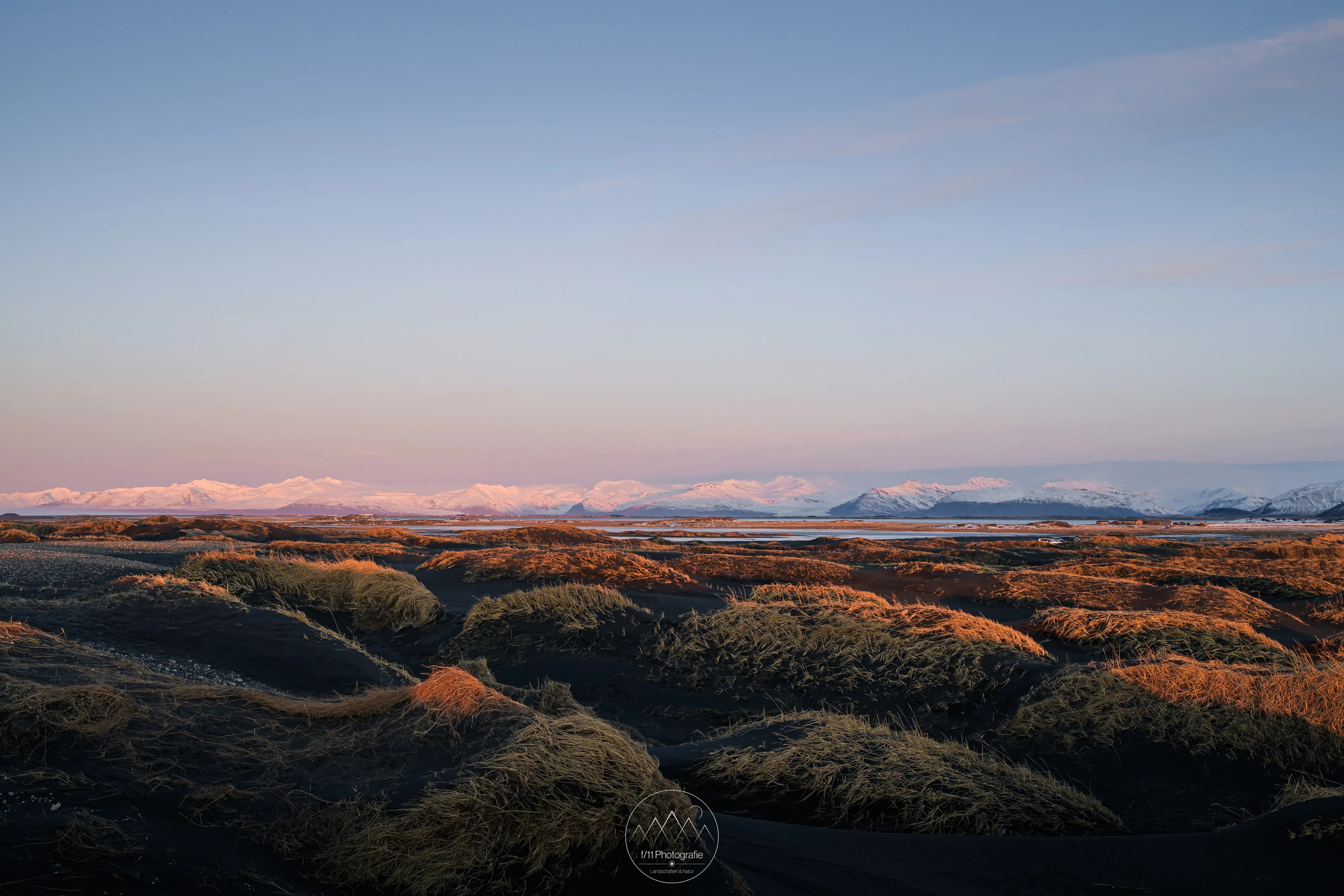 Blick über die mit Gras bewachsenen Dünen von Stokksnes zu den Gletschern Islands.
